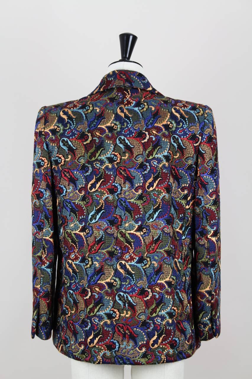 This straight-cut multi-coloured blazer is made of a rich wool that has a raised embroidered paisley pattern in silk giving it a 3D effect. It features notched lapels, shoulder pads, bracelet length sleeves with a slit, front patch pockets and a