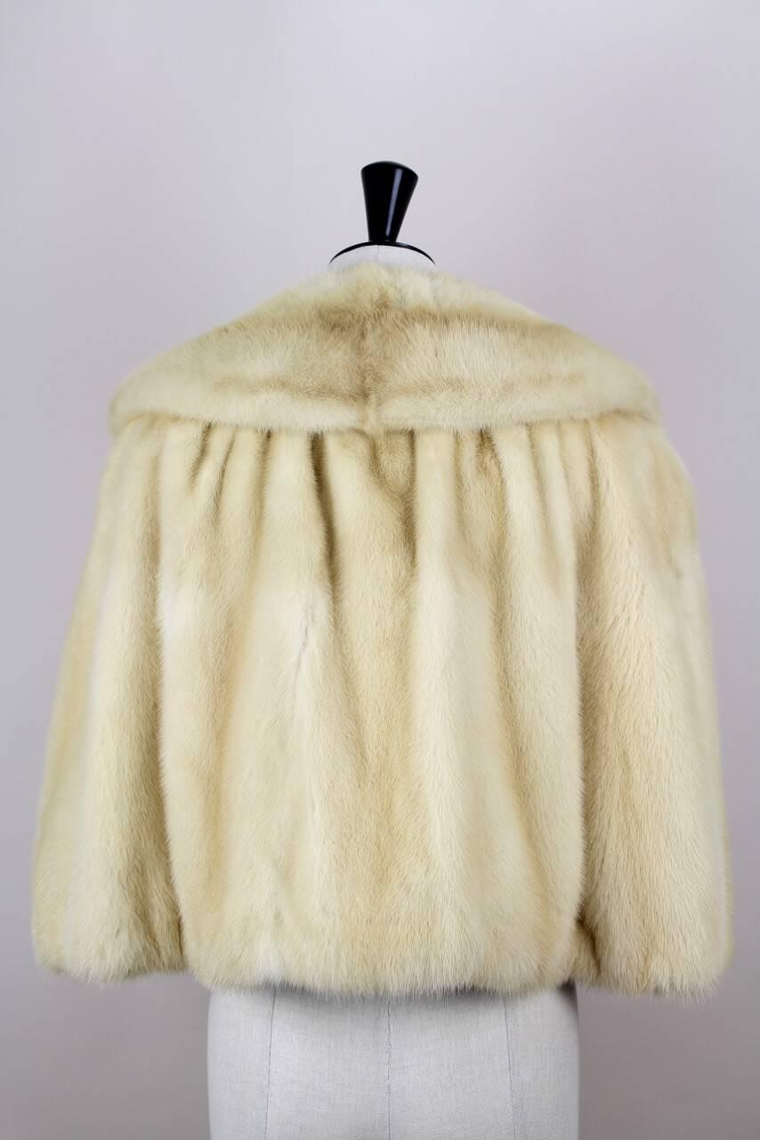 This lightweight cape is composed of champagne-coloured plush real mink fur. It features a huge fur backed collar which can be worn up or laying on top of shoulders, a gathered shoulder section and front slits for arms when closed. The cape closes