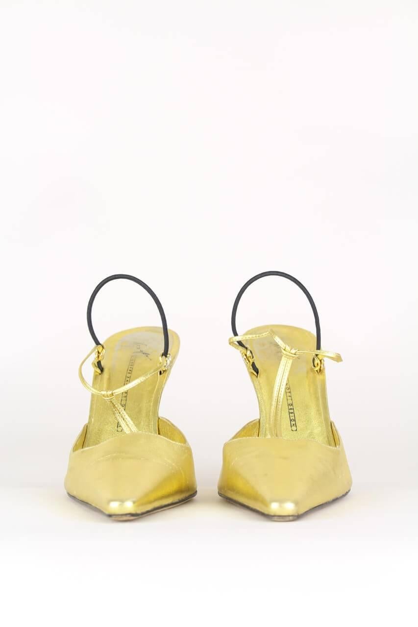These Italian crafted t-strap slingback pumps come in soft metallic golden leather and feature a pointed toe, crystal embellished straps and a pin-thin black resin stiletto heel. The heel strap is elasticated for a perfect and comfortable fit. They
