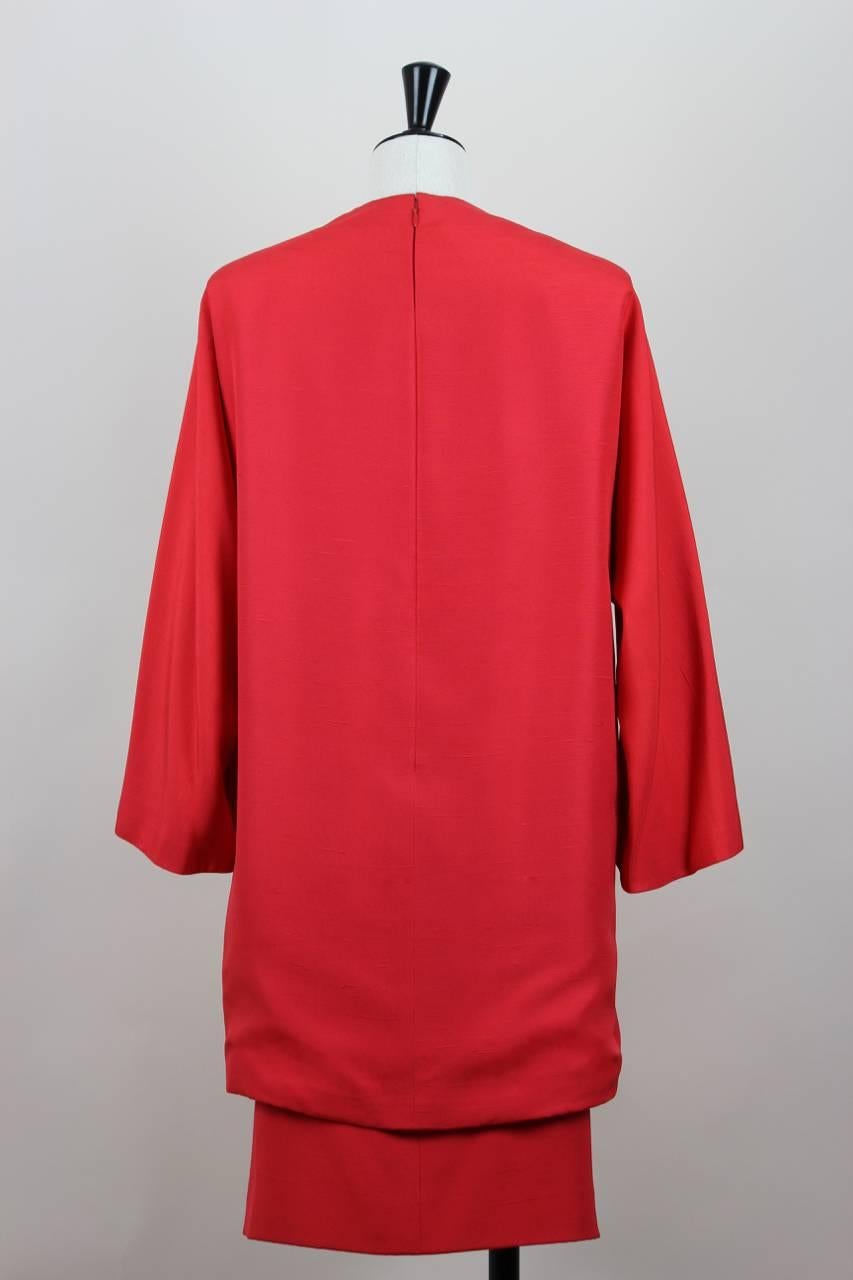 This early 2000s Yves Saint Laurent tunic and skirt set is made from scarlet red very delicate raw silk. The straight-cut tunic top features a demure neckline, long sleeves (cut in one with the dress at back), a hem slit at the left front, a slit