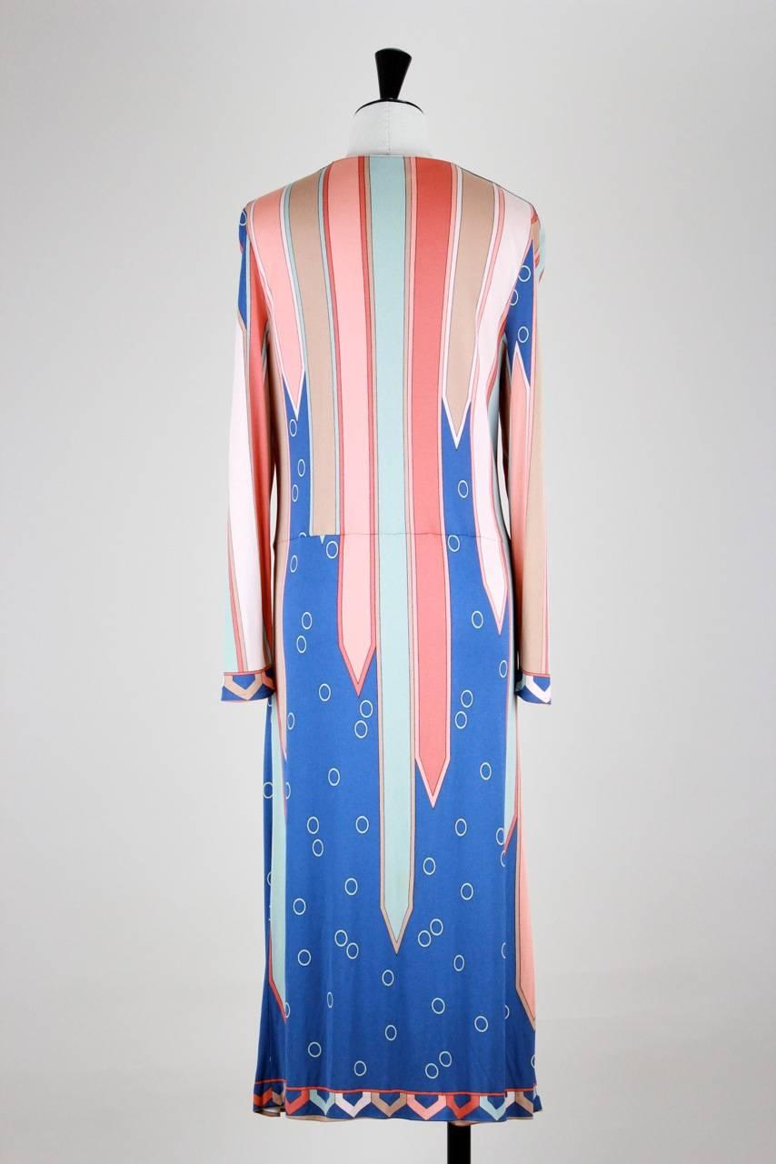 This unusual Pucci silk jersey dress shows the iconic "Vivara" print - an art déco like geometric print in shades of blue and rose. It has a round neckline, long sleeves and ends mid calf. A seam runs around the dropped waist. The dress
