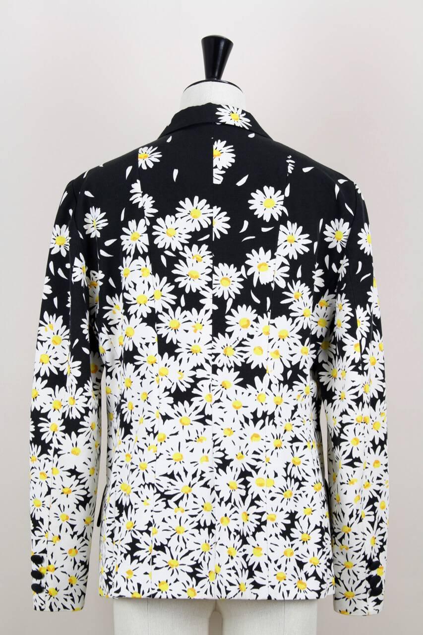 This lovely Spring/Summer 1996 documented (see last picture) Moschino double-breasted black blazer shows an all over daisy print in white and yellow and is made from a slightly structured cotton blend. It features a peak lapel collar, long buttoned