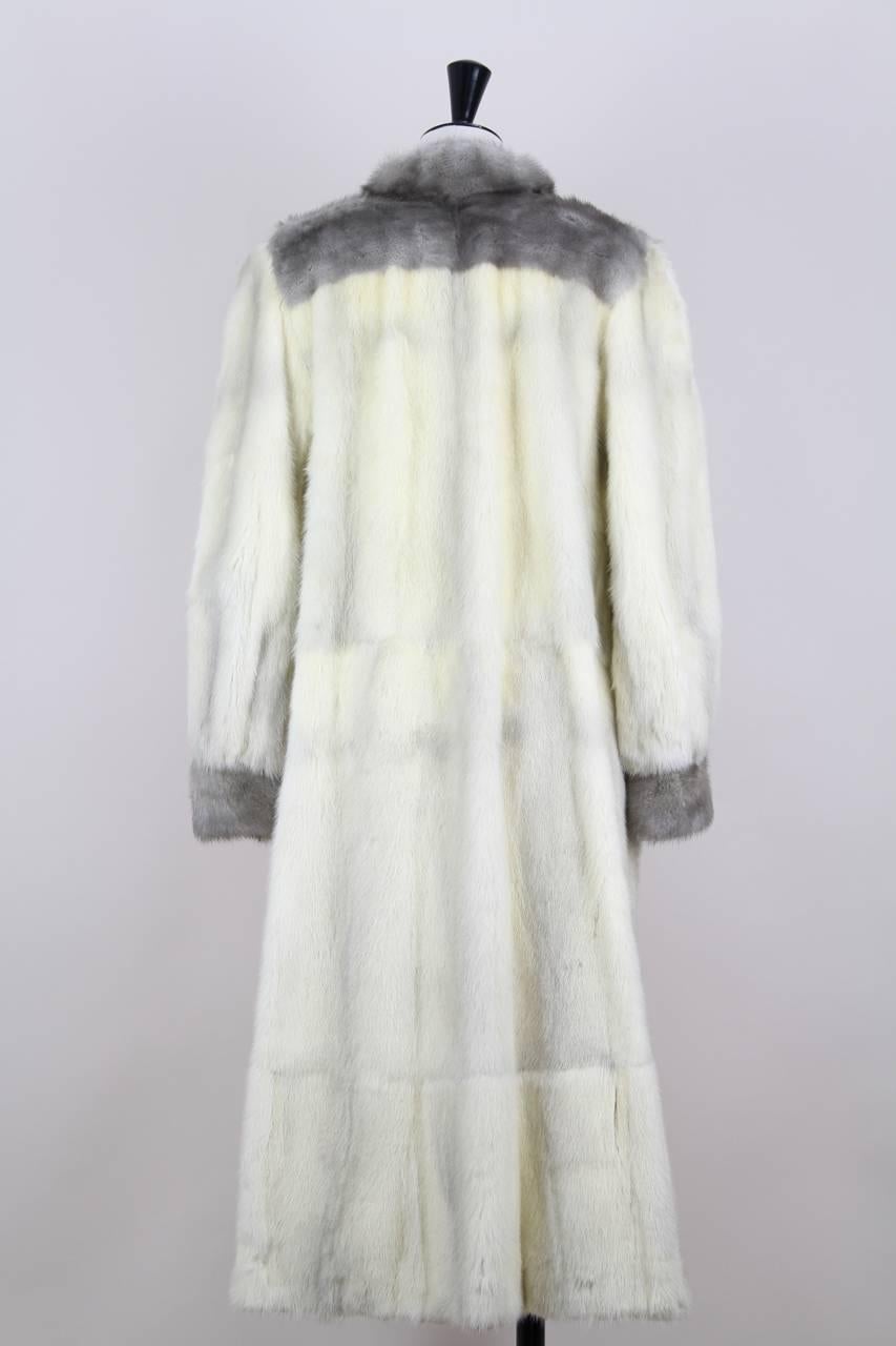 This calf-length coat is crafted from off-white cross mink fur with grey guard hairs. The collar, shoulder section, front hemline and cuffs are framed with light grey sapphire mink. It features a slight A-line shape, long full sleeves with cuffs and