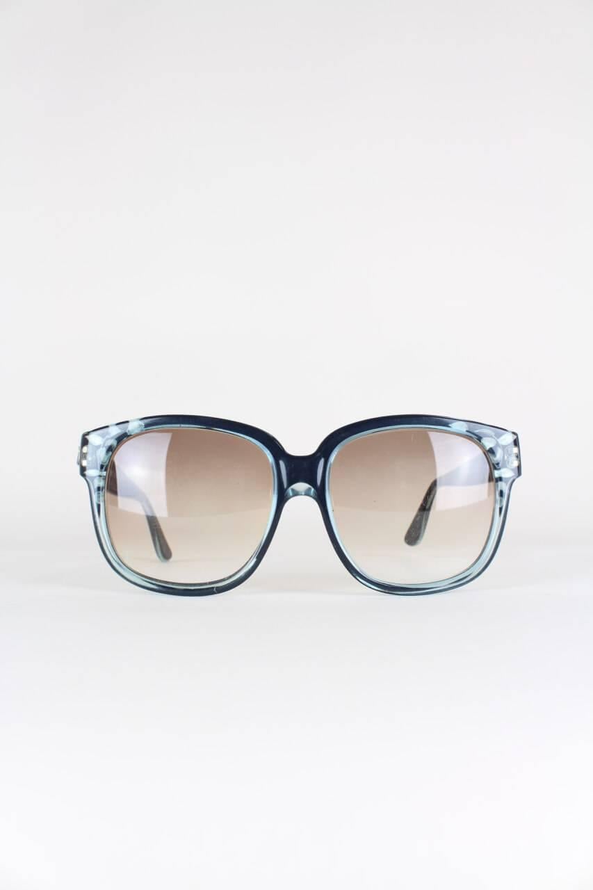 These rare and sought after model 8080 sunglasses are hand made in France and feature an oversized clear blue frame that is shaded in black. The edges are decorated with leaves-like cut-outs creating a three-dimensional effect. It comes with its