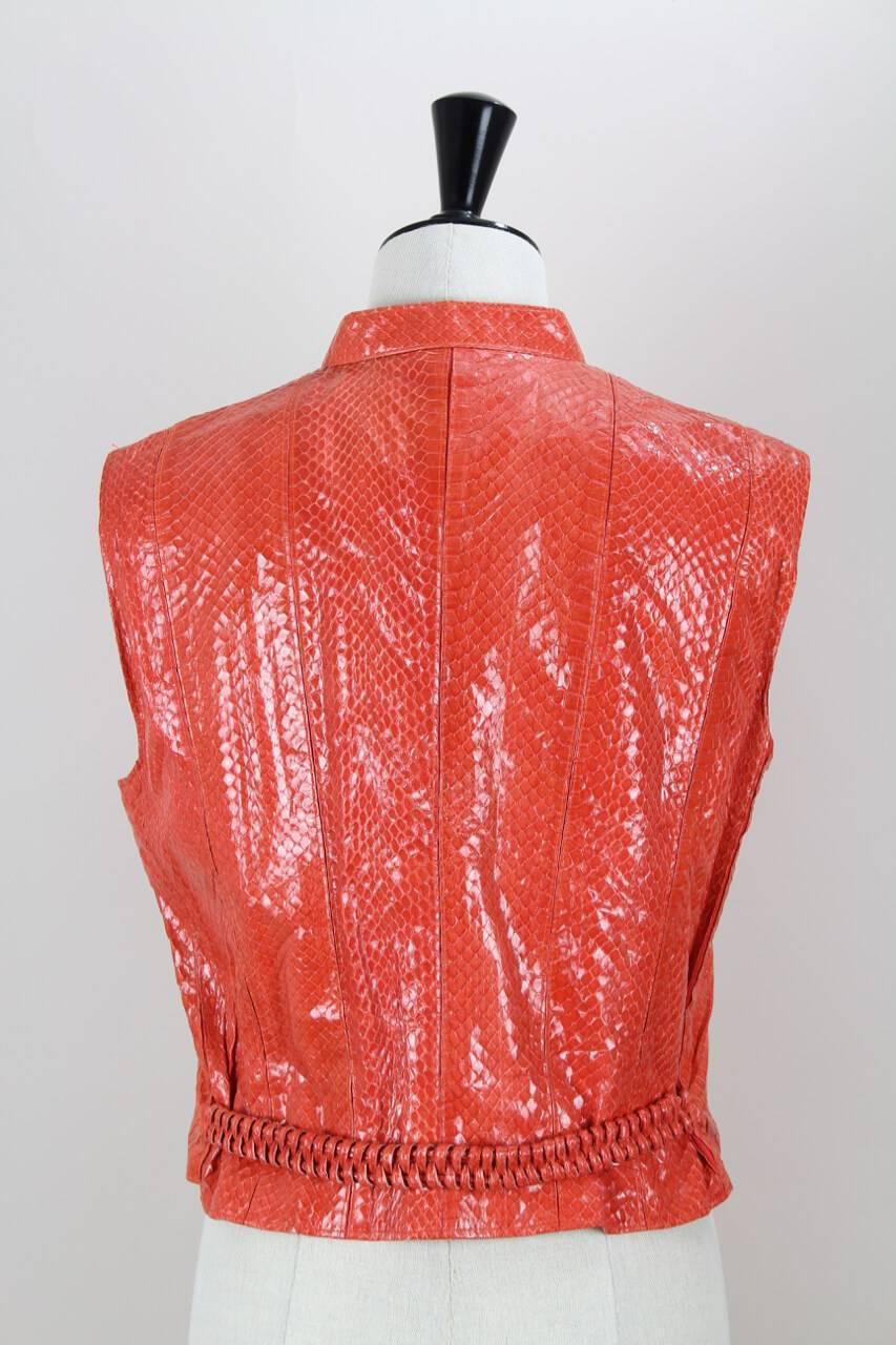 This handmade strawberry red vest is made from soft snakeskin and feautures a small stand-up collar, colour-coordinated elastic insets between the leather stripes and a braided half belt in the back. It is fully lined in red logo print acetate and