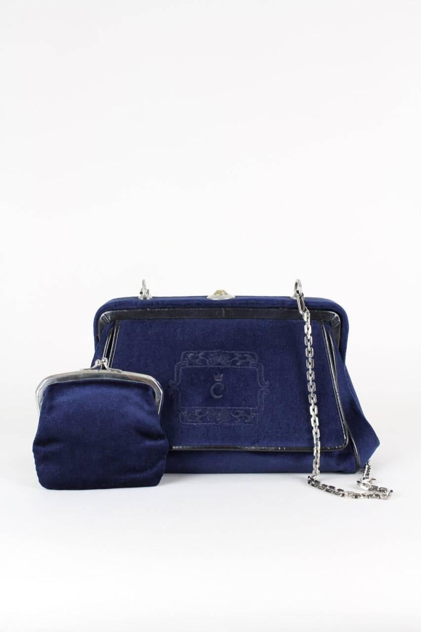 This frame based doctor style shoulder bag features an ornamental crest-like tonal embroidered design on the center front flap depicting the company's logo 