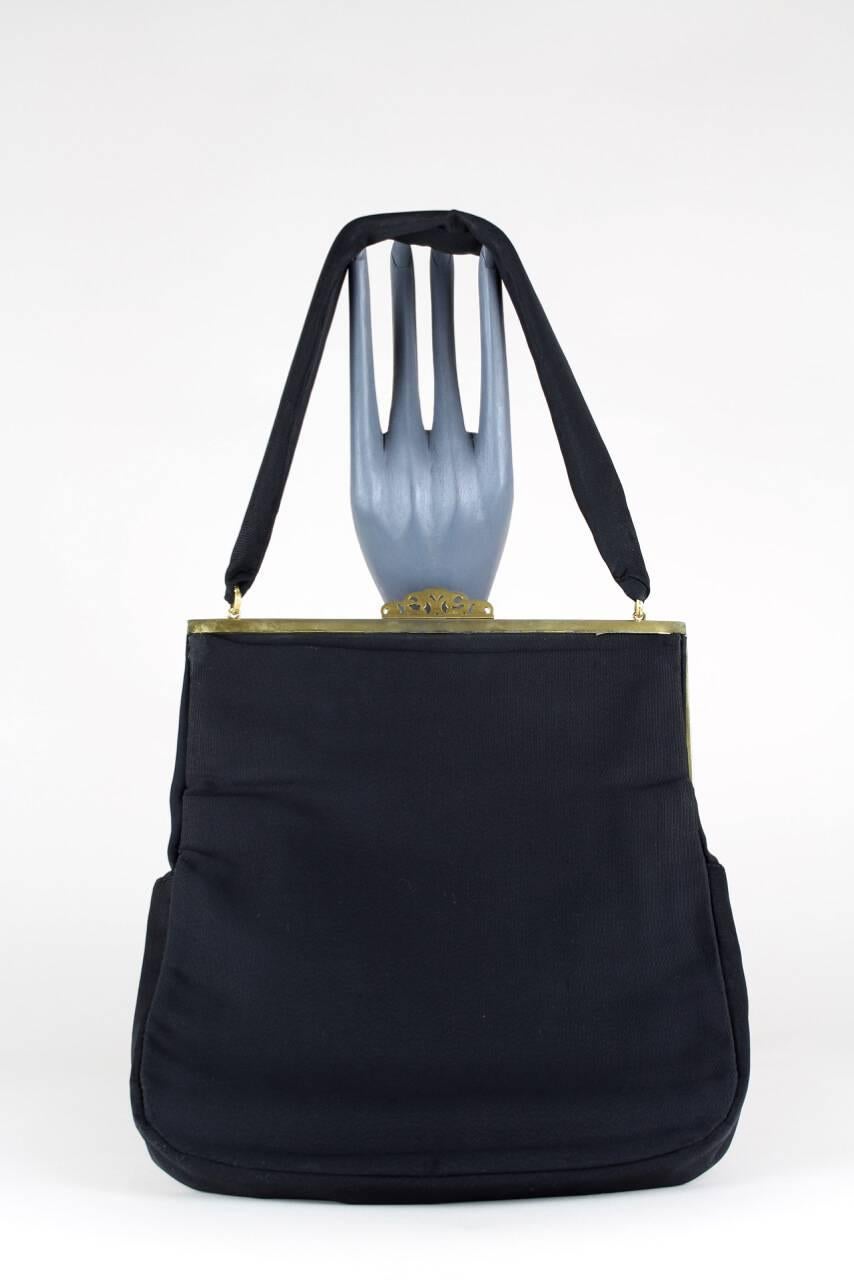 Ce sac à main Art nouveau est fabriqué à partir d'un tissu noir épais de haute qualité et comporte un cadre en métal de couleur dorée richement décoré de belles fleurs et feuilles découpées, une fermeture à pression et une poignée unique en tissu