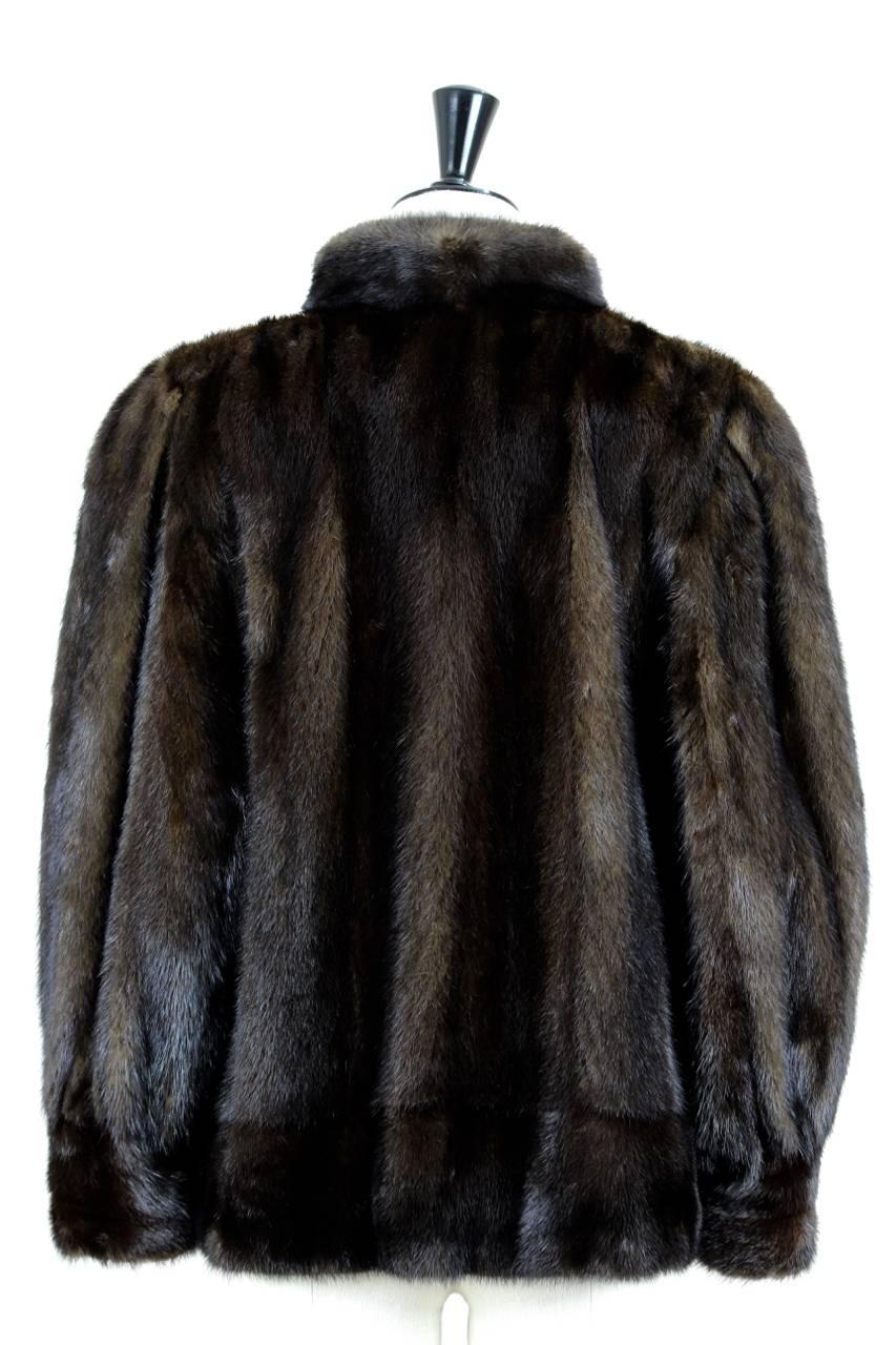 This hip-length straight-cut jacket is made from dark chocolate brown real mink fur. It features a stand-up collar, long roomy sleeves gathered in wide cuffs, two velvet lined patch pockets at hips and one hidden inner pocket. It is fully lined in