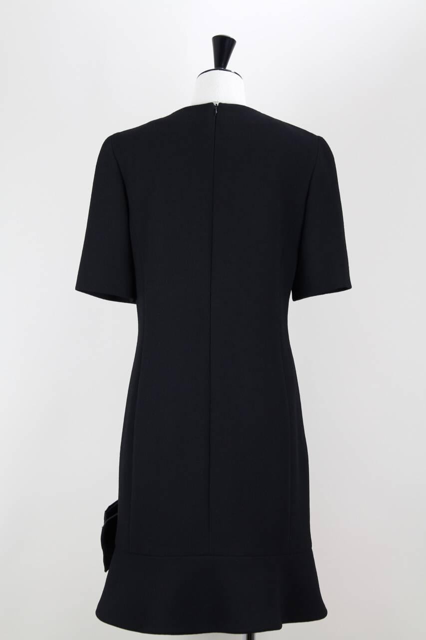 This shift dress is made from pure black wool crepe and features a crew neck with a split, short sleeves, darts at bustline and a 13 cm – 5.1
