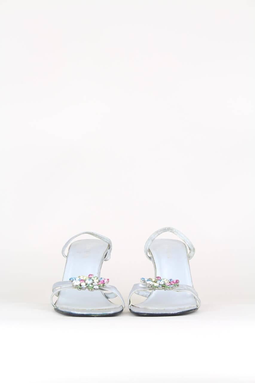 These metallic silver leather strappy sandals crafted in Italy are embellished with beautiful pastel-hued different-sized rhinestones at the front. They feature an open soft square toe, an elasticated slingback strap, a high mirrored metallic