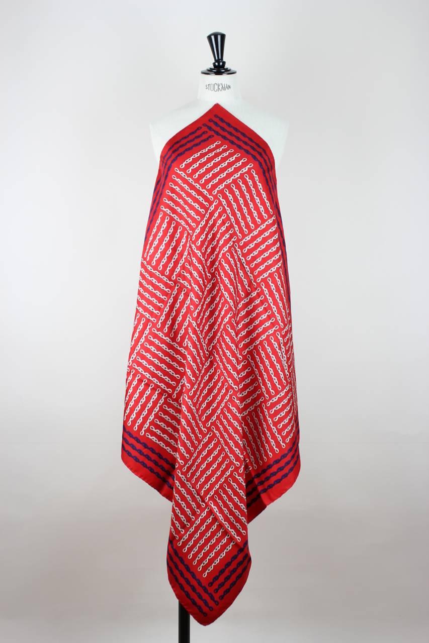 This scarf features a beautiful signature print of intertwined Roberta di Camerino belts in white and navy on a red background. It is made from silk twill, has hand-rolled edges and is signed 