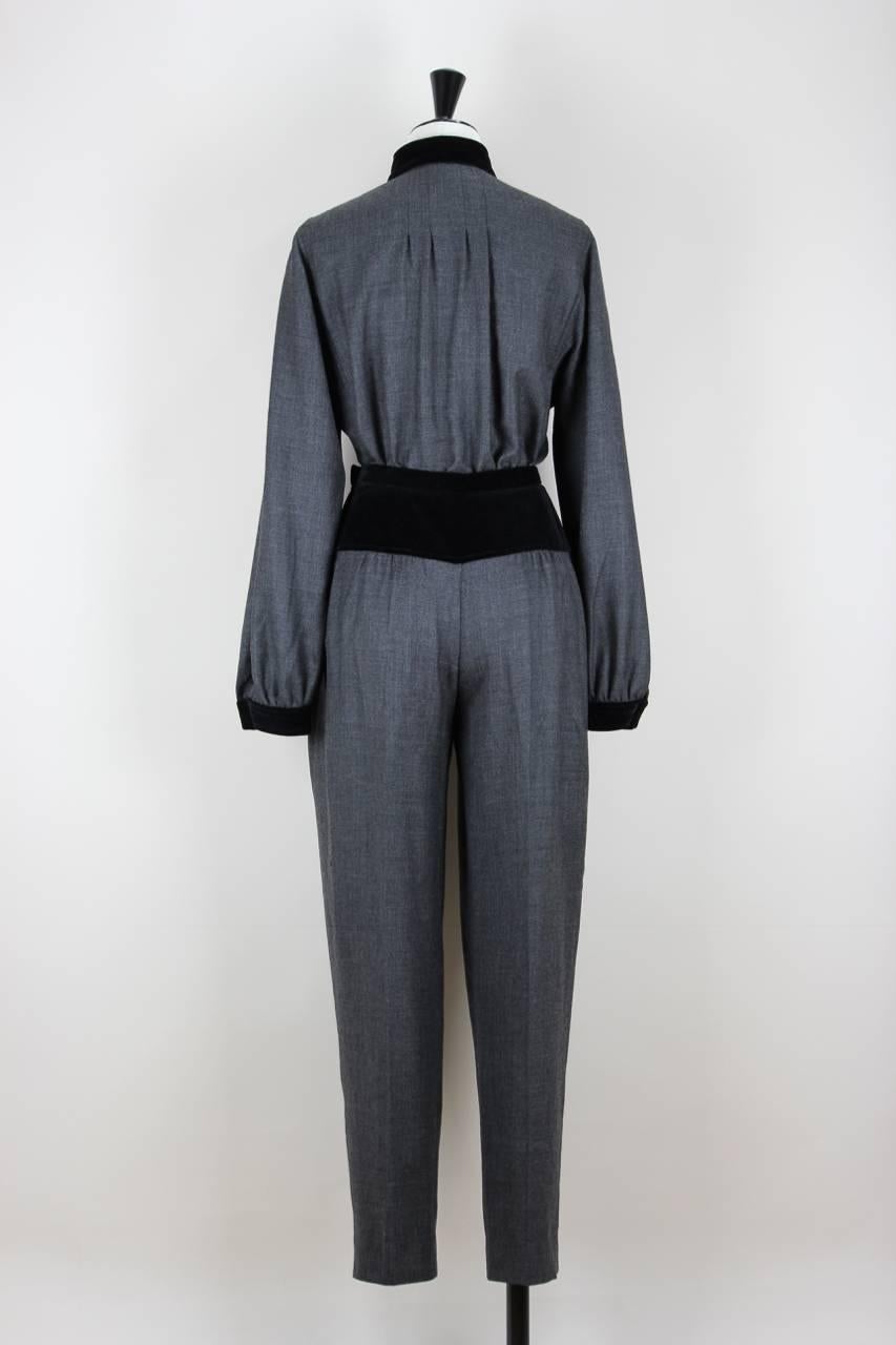 This blouse and trousers set is made from charcoal grey soft wool with black velveteen trimming. The blouse is unlined and features a mandarin collar in black velveteen, a double-breasted buttoned front, pleated details on the upper part of the