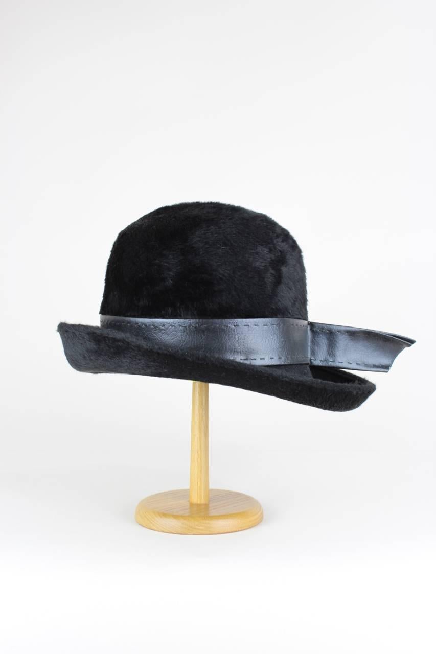 This dressy bowler style hat has an upturned brim and is made from black hare fur (crown and outside of the brim) and wool (inside of the brim). A black faux leather band circles the crown. The hat is unlined and there is a black grosgrain ribbon