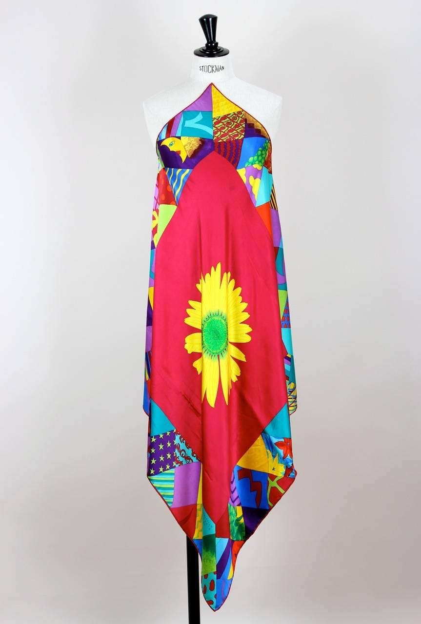 The kaleidoscopic colours and print of this gorgeous square silk scarf burst with energy and life. The center features a big yellow sunflower, the border a geometric pattern in turquoise, yellow, red, blue, green and purple. It has a hand-rolled red