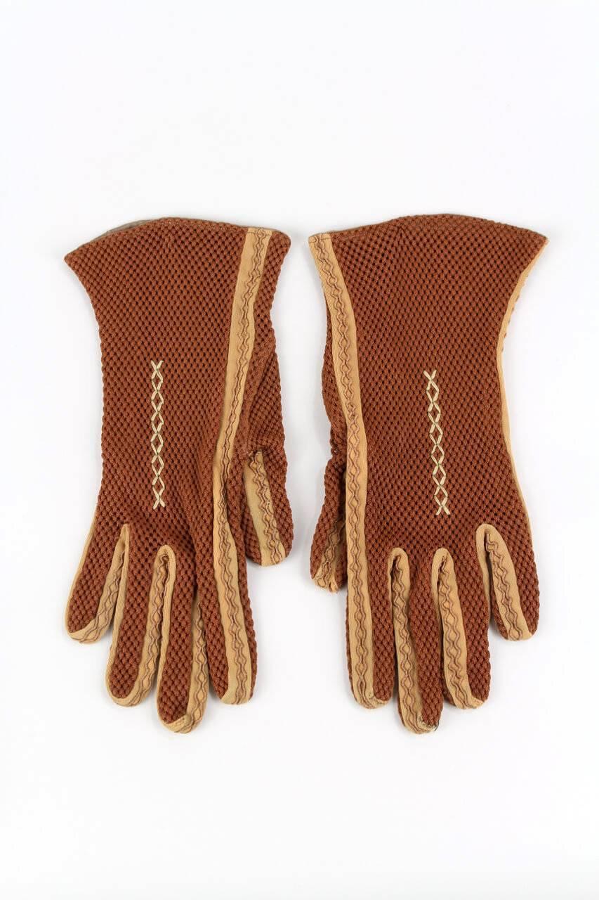 Extraordinary 1930s/1940s rust-coloured mesh gloves with contrasting seams in apricot-coloured fabric that are embroidered with a matching yarn. Additionally the back of the hand is decorated with a cross stich embroidery. Lovely smooth material!