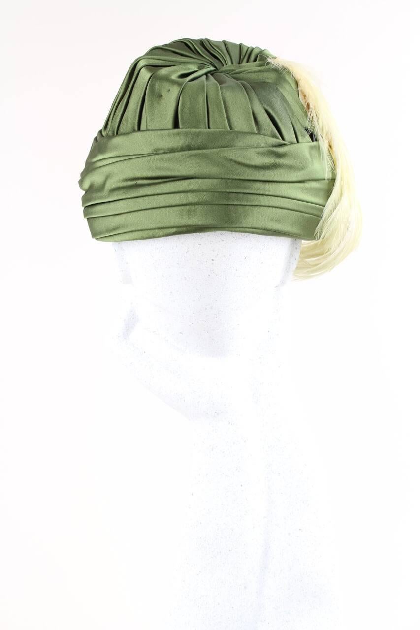 Fantastic 1950s numbered, possibly haute couture, olive green silk satin vintage hat adorned with peach feathers at the right side. Beautiful details of pleating, folding and twisting! The hat has an interior olive green grosgrain ribbon band, is