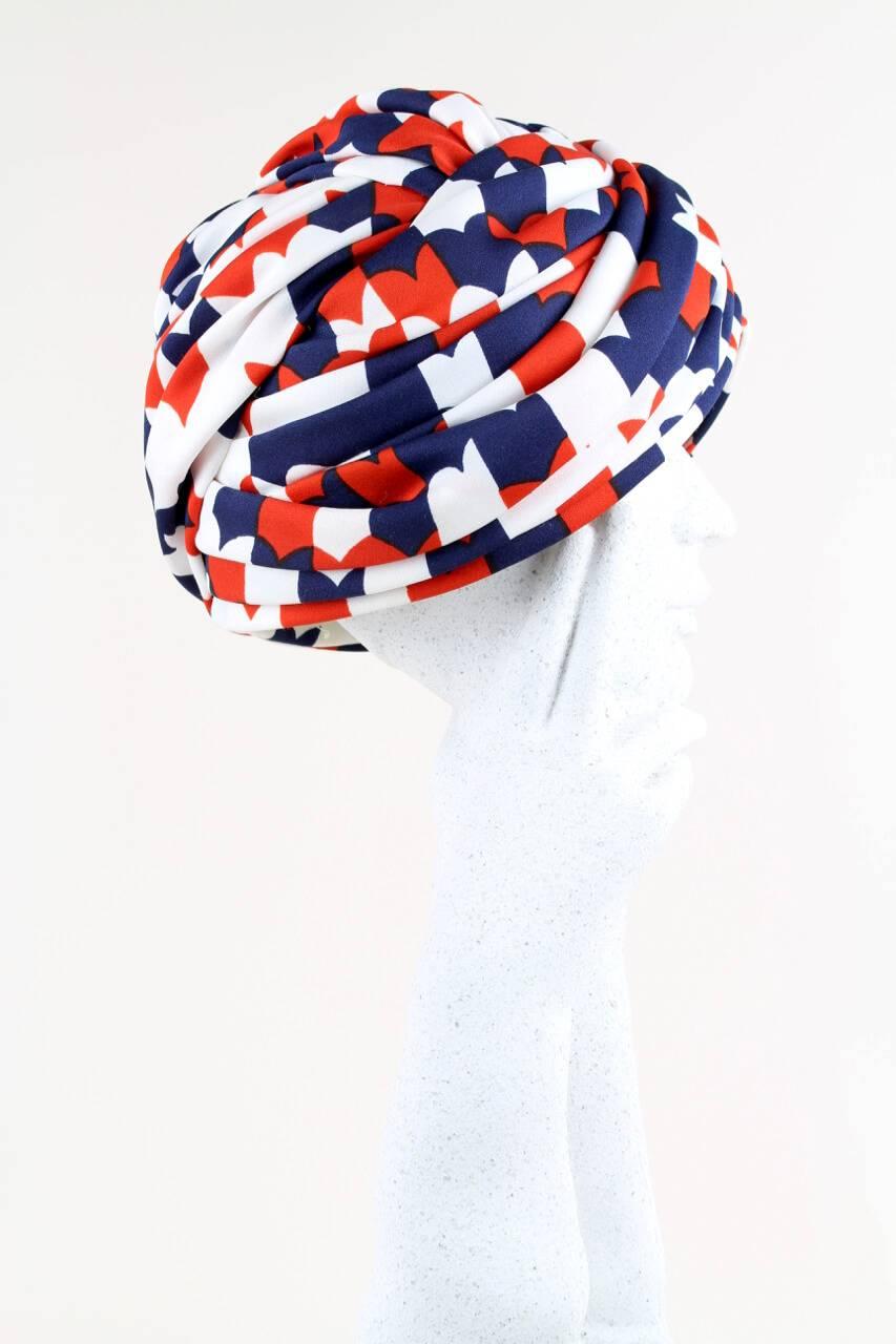 This beautifully draped 1950s/1960s turban hat is hand-made from a soft fabric with a lovely stylized heart print in navy, cherry-red and white. Gorgeous details of pleating, folding and twisting. The hat has an interior cream grosgrain ribbon band