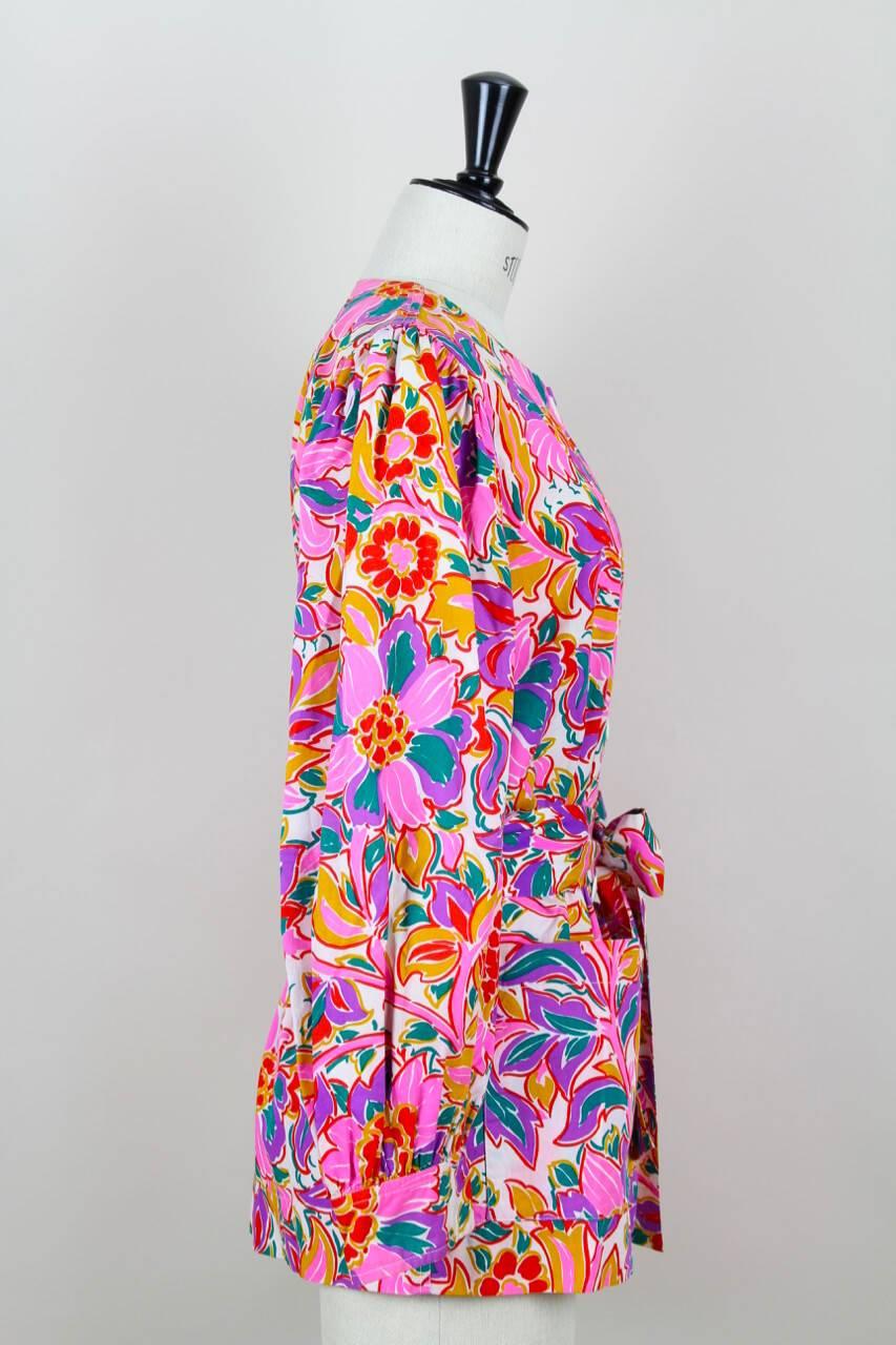 This vibrant multi-colour floral print vintage Yves Saint Laurent blouse or tunic is a loose fit design fashioned from a crisp cotton. It features a crew neck, full sleeves with soft pleating at the shoulders, cuffs, patch pockets at the front, belt