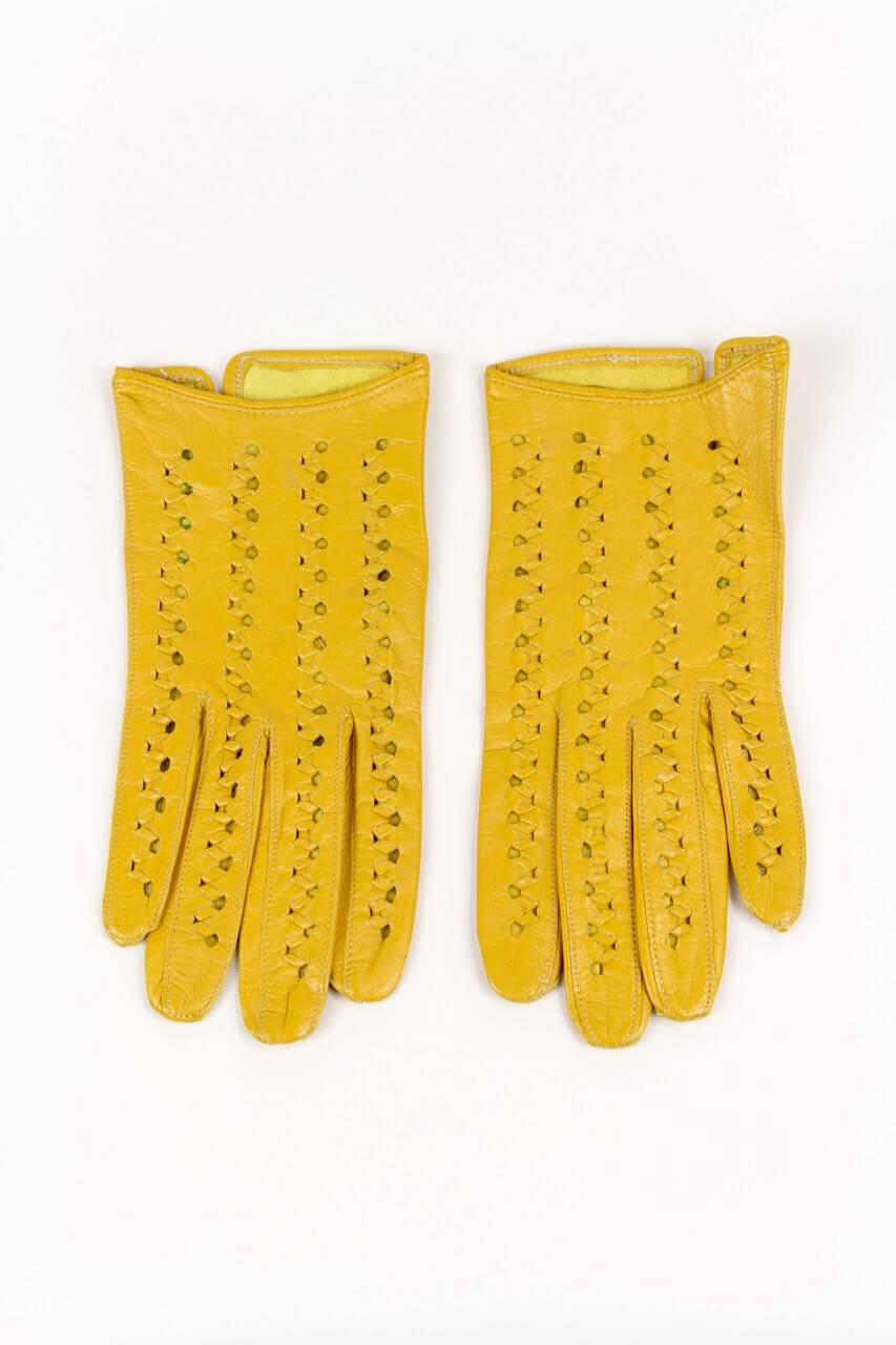 Eye-catching short and airy sunflower yellow smooth leather gloves. The upper side features a decorative punched and woven design. The gloves are unlined and measure 19,5 cm – 7.7