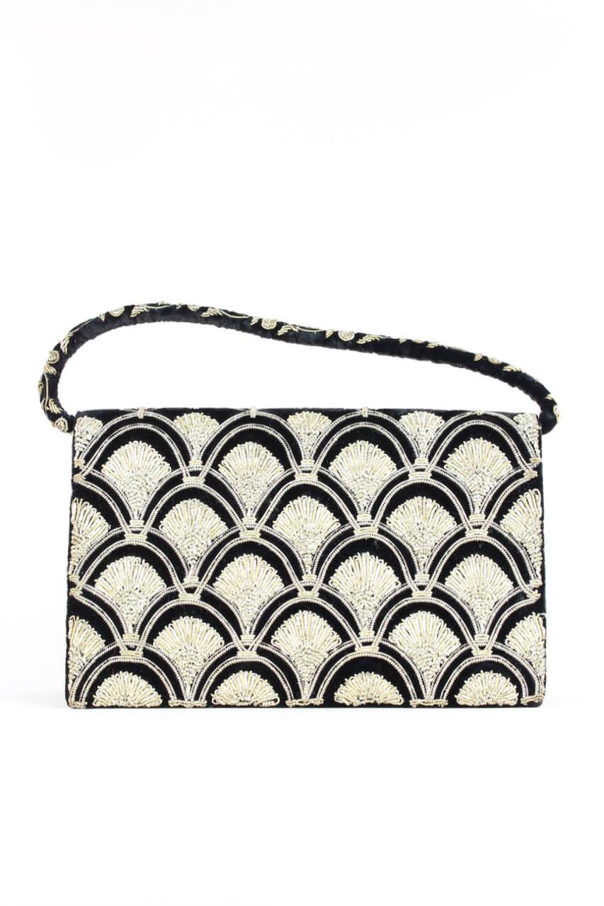 This elegant rectangular black velvet evening bag is decorated with a wonderful rich 3D quality arched Art Déco style Zardozi embroidery on both sides. The embroidery is all done by hand in silver metallic threads that have a warm tint. A short