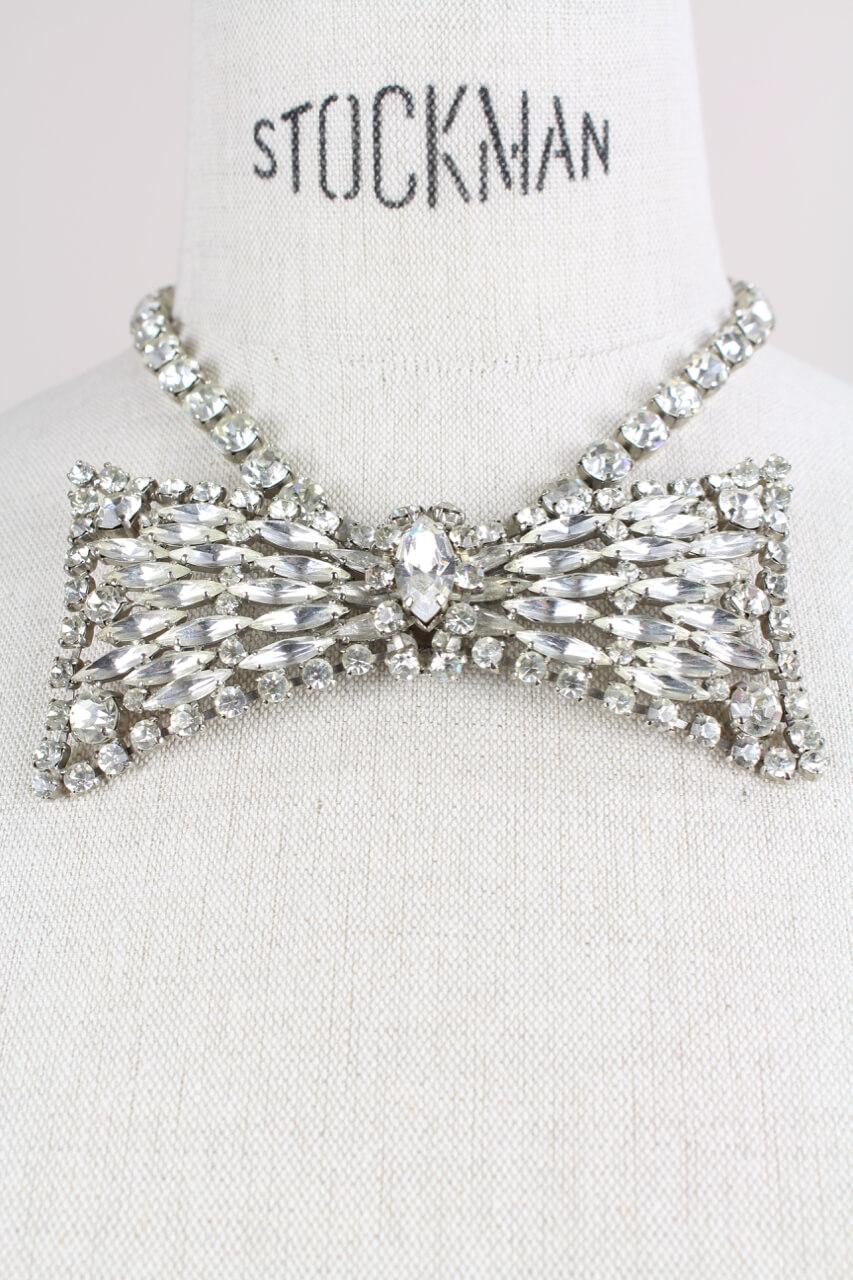 Dainty bow tie design clear rhinestone encrusted necklace probably from the 1950s. The perfect bow tie in the front features a large Navette-cut rhinestone in the center surrounded by various smaller Navette- and brilliant-cut rhinestones, all in a