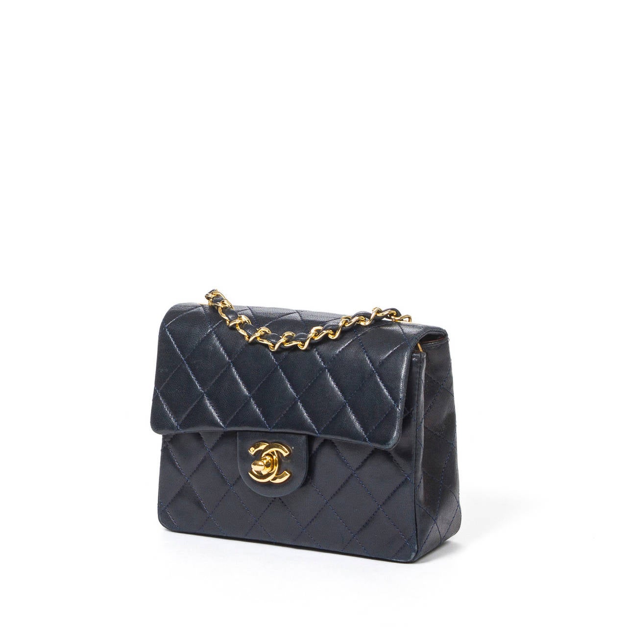 Mini Classic flap bag in navy blue quilted leather with chain strap interlaced with leather, CC turnlock and gold tone hardware. Burgundy leather lined interior with one zip pocket and one slip pocket. Authenticity card included.  Excellent