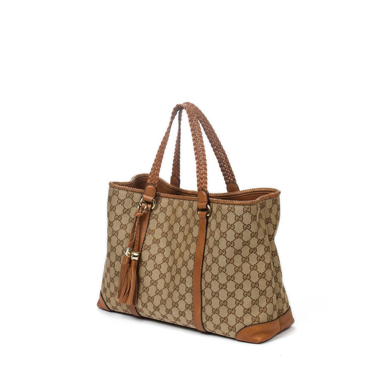 Gucci Tote in beige monogrammed canvas with tan leather braided handles with tassel pendant and gold tone hardware. Line interior in beige canvas monogram with zip compartment, 2 slip pocket and one zip pocket. Close to new condition.