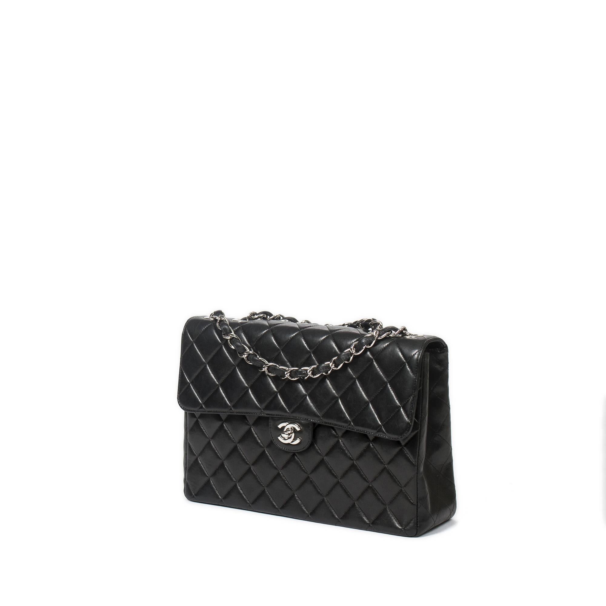 Chanel Classic Jumbo in black quilted leather with double chain strap interlaced with black leather (drop: single chain:63cm, double strap: 33cm). Silver CC turnlock and hardware. Interior in burgundy leather with one slip pocket and one zip pocket.