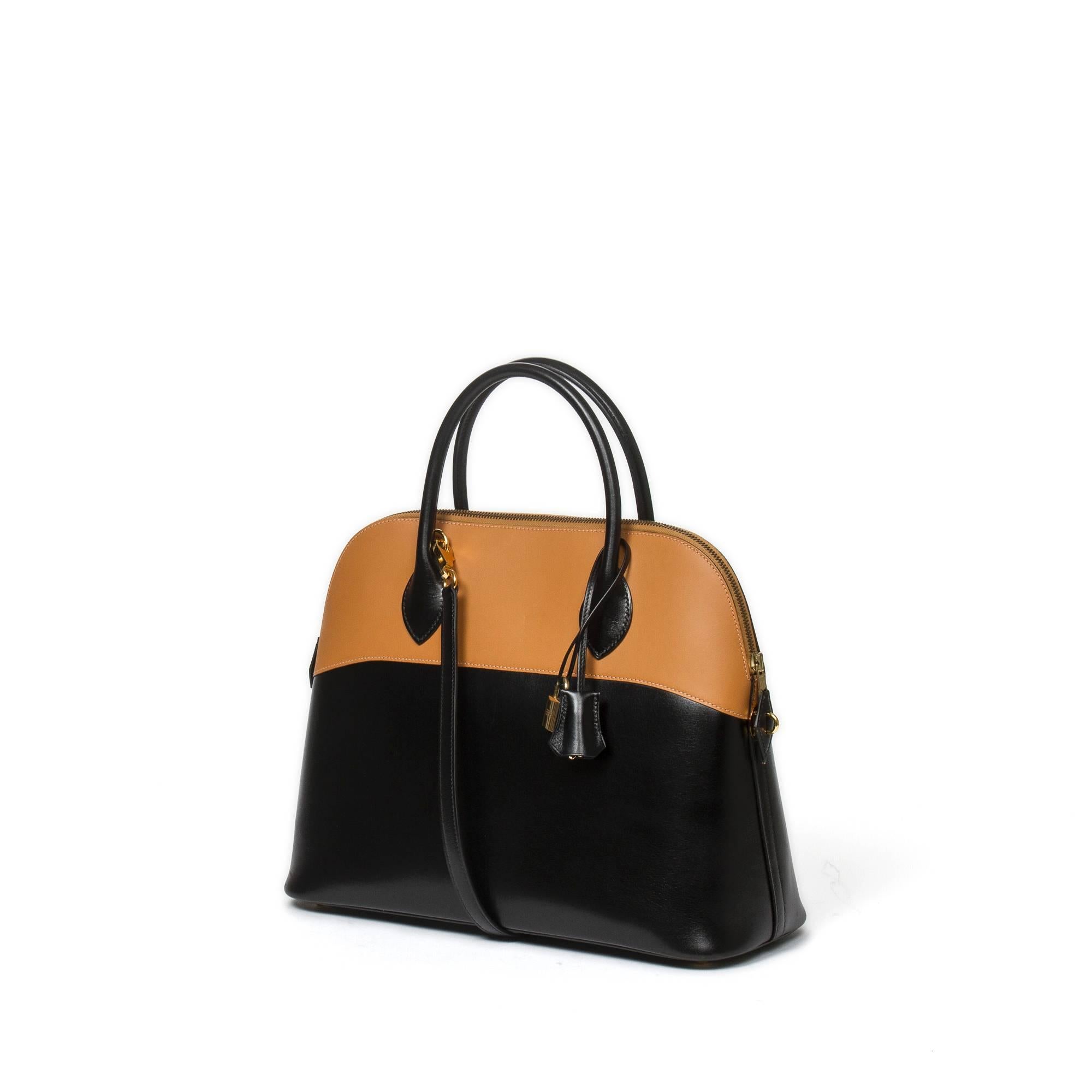 Hermès Bolide Bicolor 35cm in black Box and gold Chamonix leather with black leather handles (9cm), black leather strap (40cm), cadenas and keys in clochette and gold tone hardware. Black leather interior with one slip pocket. Pouch for