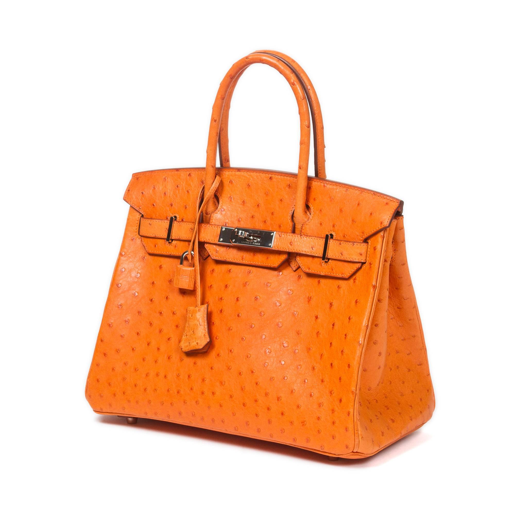 Beautiful Birkin 30 in Tangerine ostrich skin with cadenas and keys in clochette, silver tone hardware. Orange chèvre leather lined interior with one slip pocket and one zip pocket. Stamp F in square. Model from 2002. Dustbag included. There are