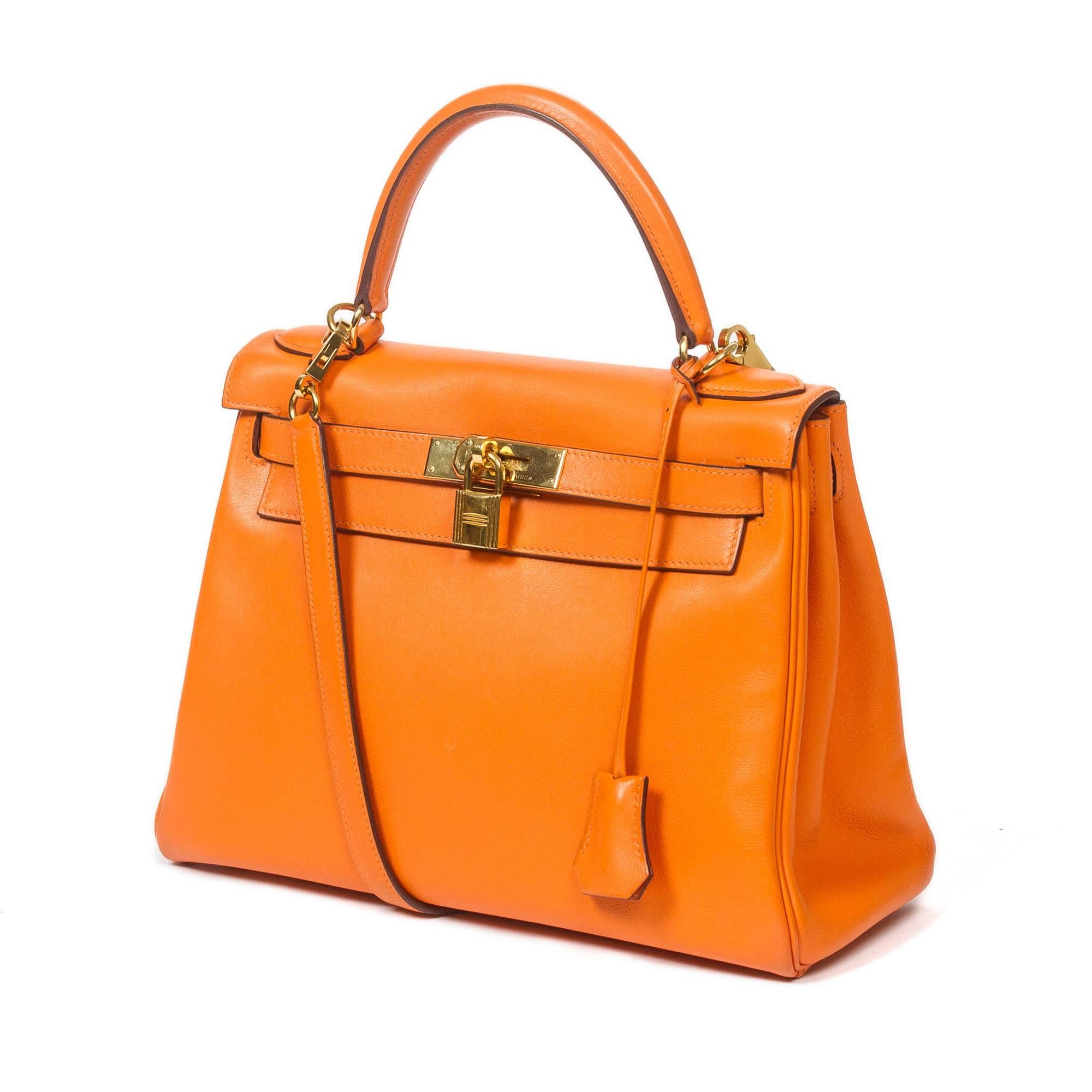 Kelly Retourné 28 in orange Swift leather with strap, cadenas and keys in clochette, gold tone hardware. Orange leather lined interior with 2 slip pockets and one zip pocket. Stamp K in square. Model from 2007. Dustbag included. Very slight scuffs