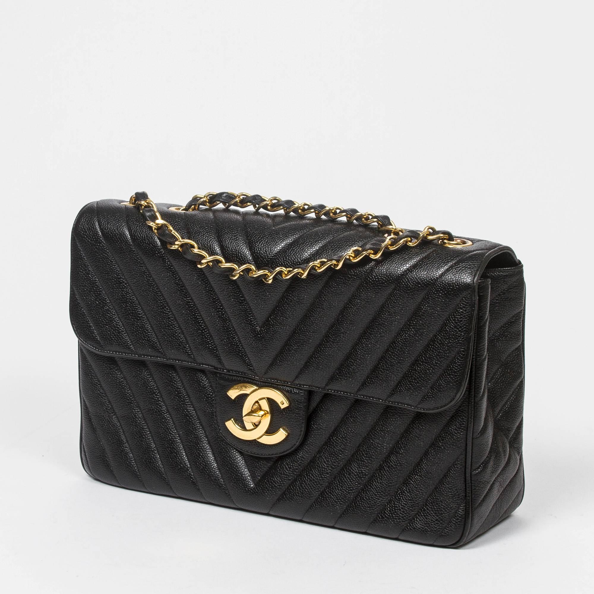 Jumbo Maxi in black chevron quilted caviar leather with double chain strap interlaced with leather, large gold tone CC turnlock. Large back slip pocket. Black leather lined interior with one slip pocket and one zip pocket. Gold tone 