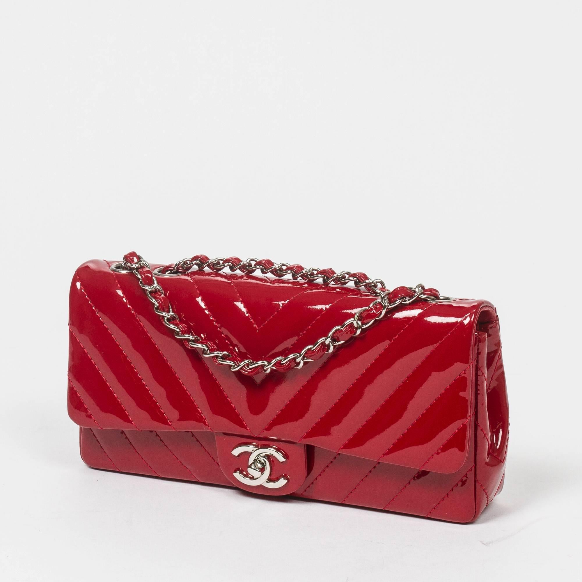 Beautiful East West Flap in deep red chevron quilted patent leather, double chain strap interlaced with red patent leather, signature turnlock, silver tone hardware. Back slip pocket. Red leather lined interior with 3 compartments. Silver tone