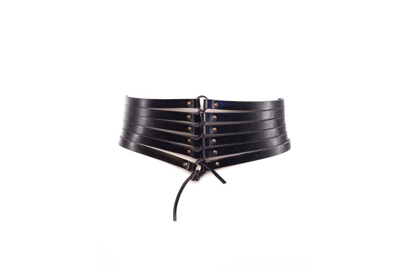 Azzendine Alaia Paris bondage leather strapped cinch belt. Belt has multi straps, brushed gold studs at each strap, a brushed gold buckle, a belt loop and a leather rope detail at the center back of the belt.