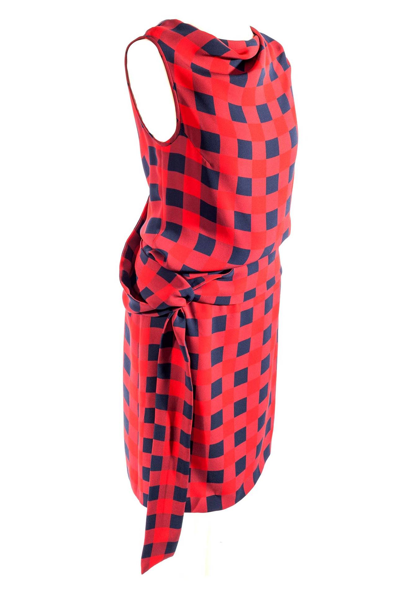 Alexander McQueen red blue plaid dress. Dress is sleeveless with boat neck and slight cowl neck. Dress has back and waist straps that tie on side, side zipper and 3 snaps. Dress is unlined.