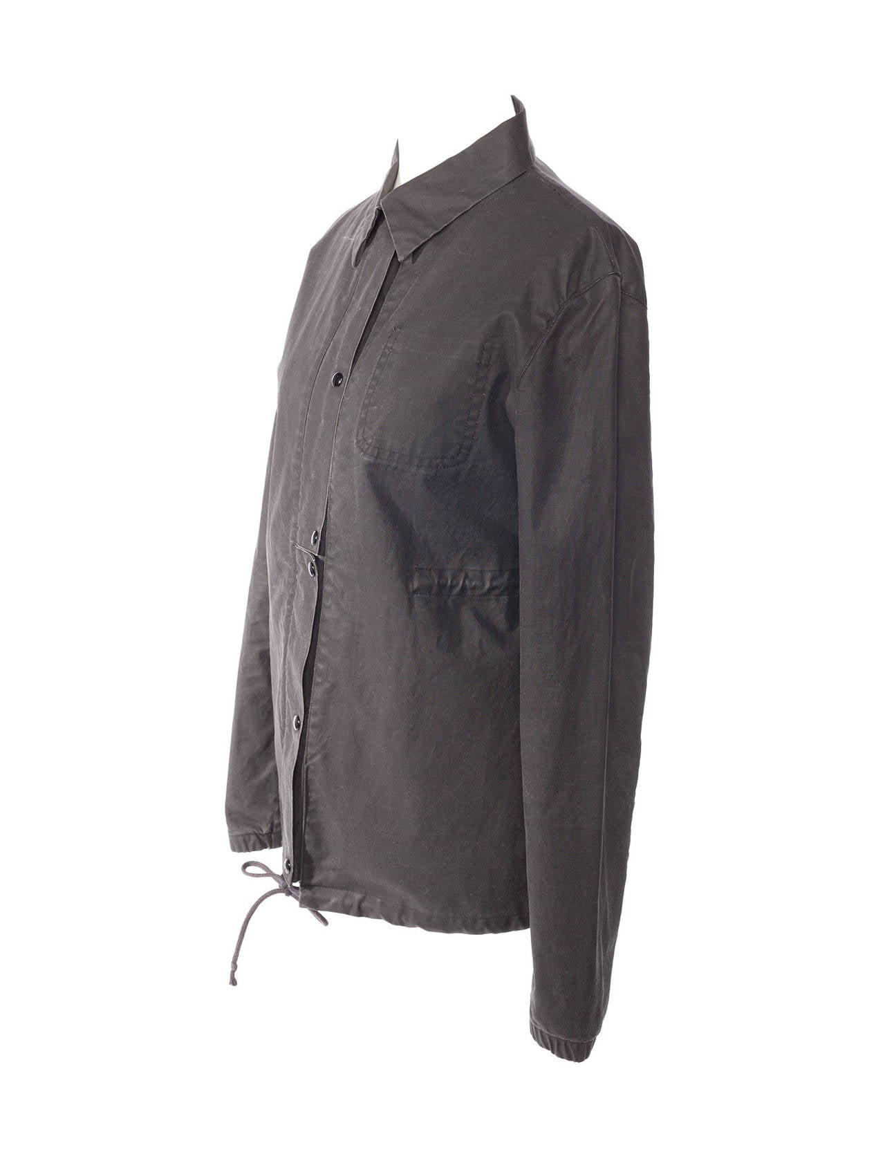 Helmut Lang 1998 jacket in grey resin cotton. Jacket is army style with shirt collar, silver zipper, 6 snaps, drawstring at waist and at hem, hidden pocket on left side chest.