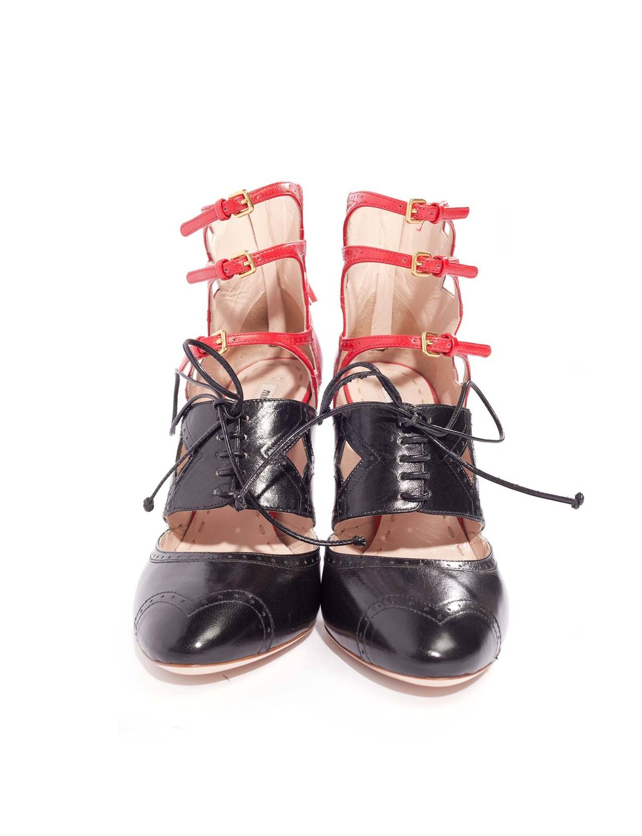 Miu Miu wingtip heels with strap details. Heels are red and black leather with perforated details all around shoes. Shoe lace closure at front and 3 straps with gold buckles.