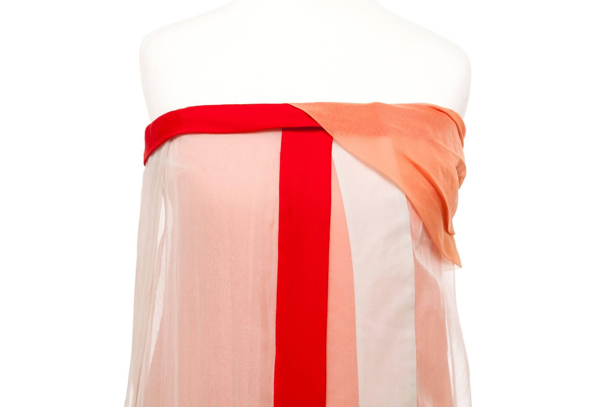 Dress is cut in multiple layers of silk with different details on each panel. The base is an orange color, with a cream layer accented with a red stripe, strapless with pleated details at the bust. Perfect for a summer event.