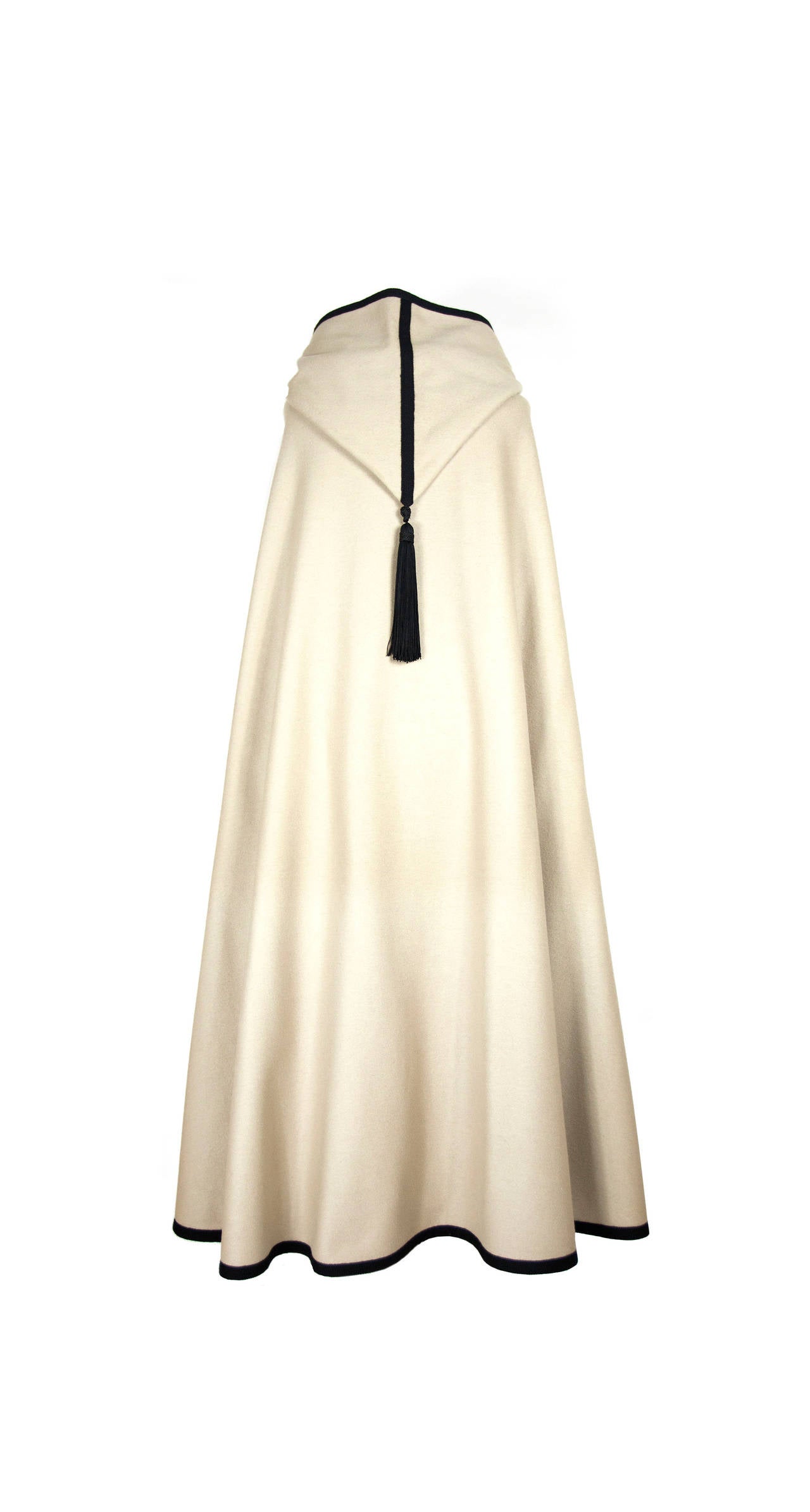 Vintage Saint Laurent Rive Gauche 1970's Loden cream cape. Cape is trimmed in a wide black braid with passementerie closures and a large tassel. Hood is oversized and has a large black tassel at its point as well. This is an iconic shape from Saint