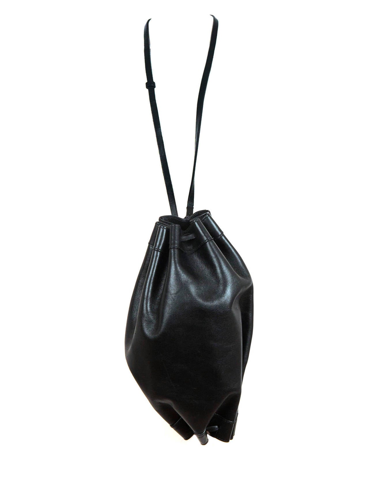 Vintage Helmut Lang football shaped bag in black leather with shoulder strap. Bag has football shape with leather cord pulled to give pleated detail all around bag. There is a long thin leather strap, fully lined in black acetate, one pocket with
