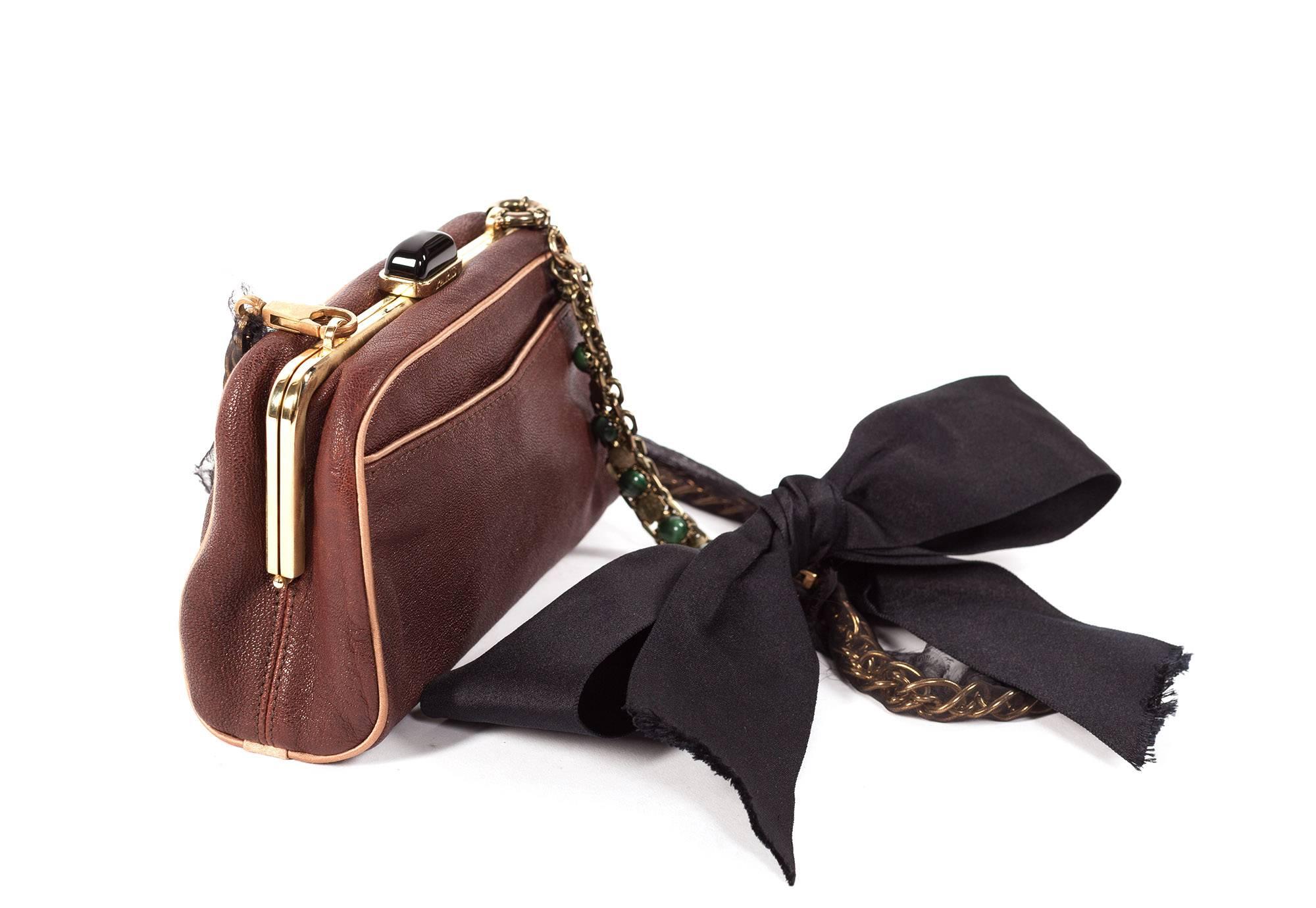 Purse comes in chocolate brown leather, tan leather trim around edges, small outside pocket, gold metal hardware with black clasp, inside is lined in satin, chain is detachable, and in gold with silk mesh overlay, large satin bow with coin logoed