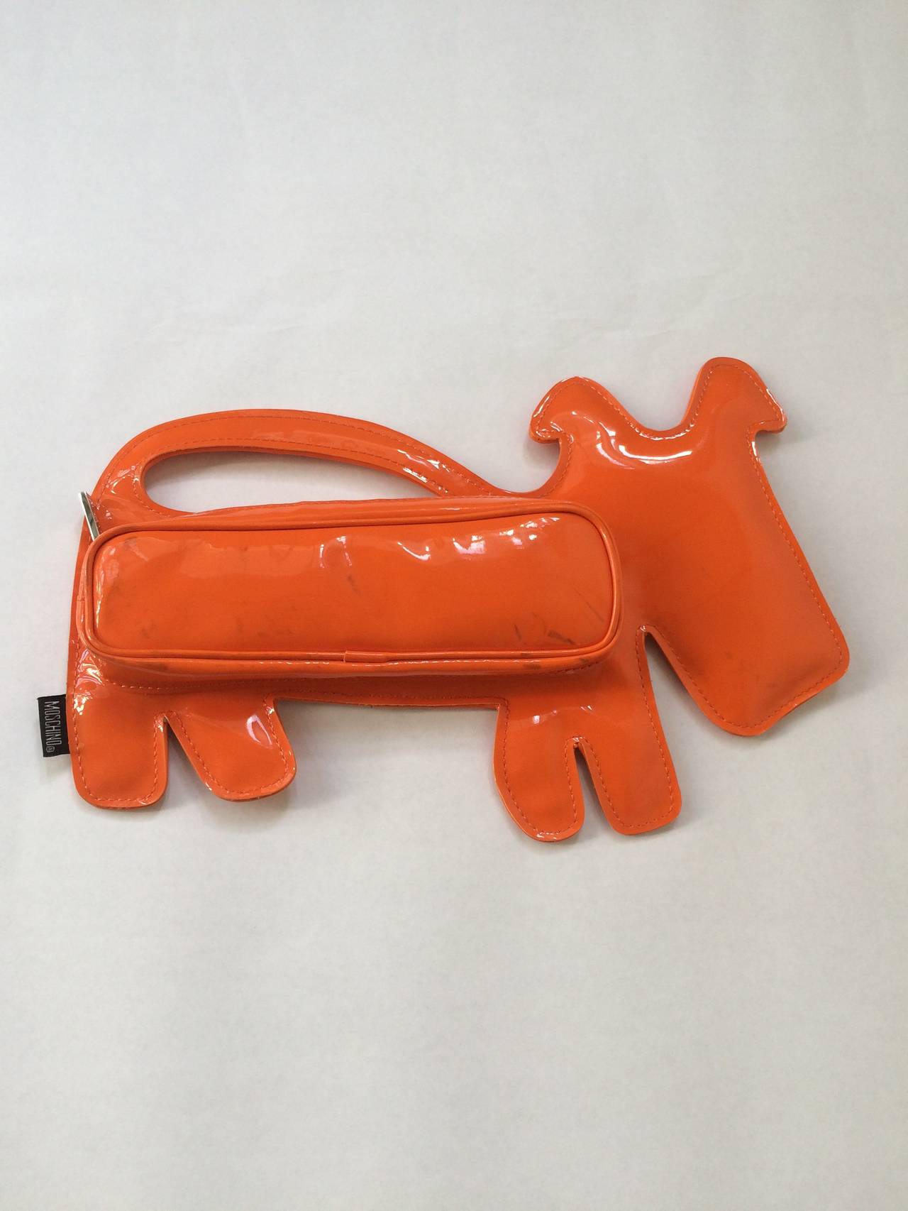 Moschino orange vinyl dog clutch / bag from the 2000s. Moschino Jeans made in Italy. Franco Moschino was born near Milan in 1950,  he studied art then began his career in 1971 as a sketcher for Giorgio Armani. This uber stylish Italian bag will have