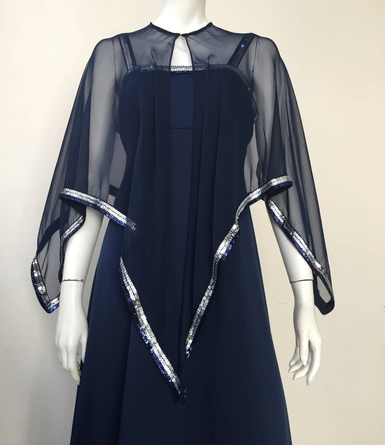 Estevez 1970s navy jersey gown & chiffon capelet both trimmed in sequin. No size tag but fits a size large. This gown will fit a woman size 10/12 but please use measurements I will provide you so that you can measure yourself to make sure it