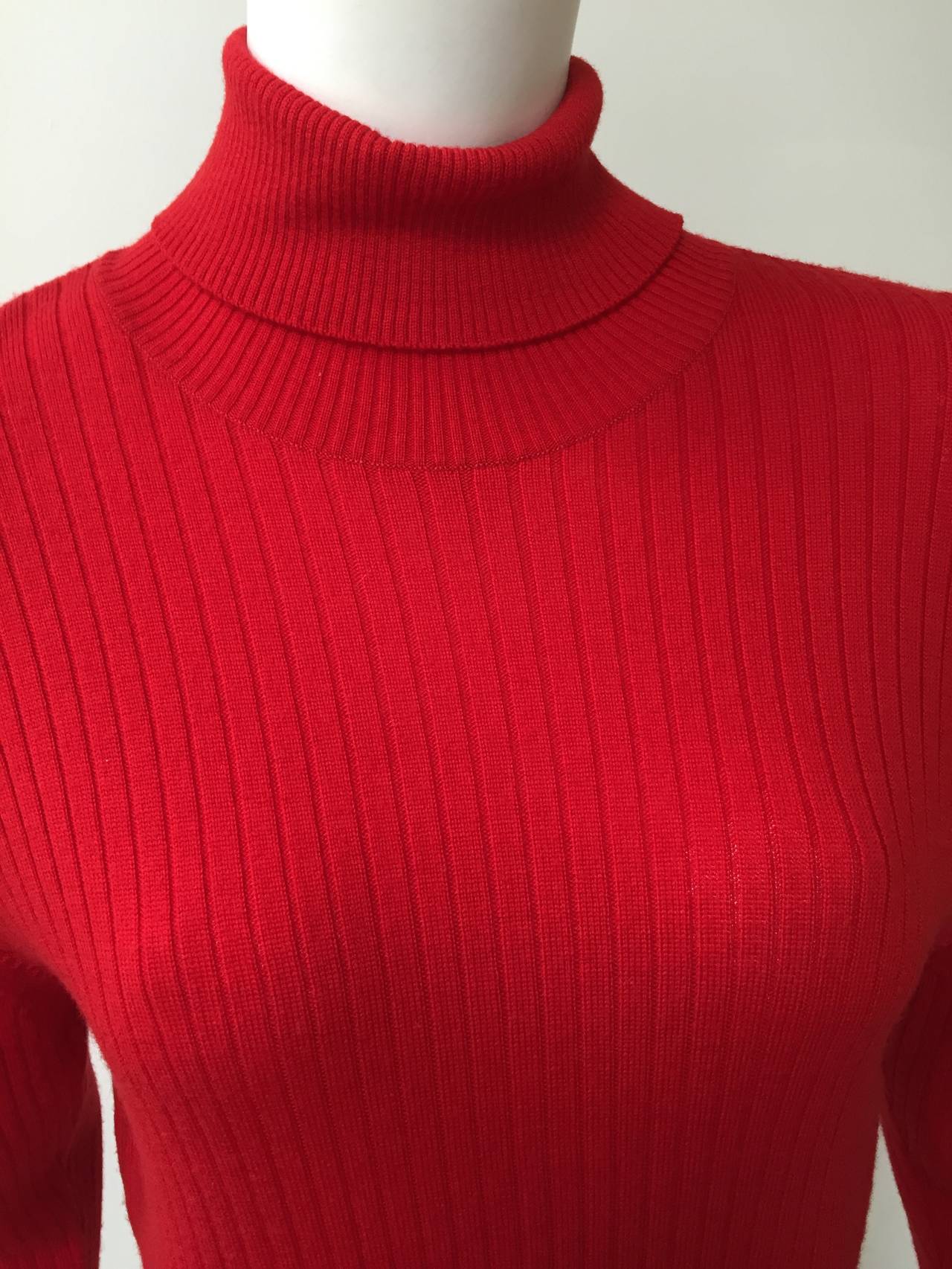 Chanel 80s red wool knit sweater size 38 fits modern day size 6 ( please see measurements). There are 3 Chanel gold logo buttons on each cuff and 4 Chanel gold logo buttons at back of neck. Ribbed band at bottom. Depending on height this top can