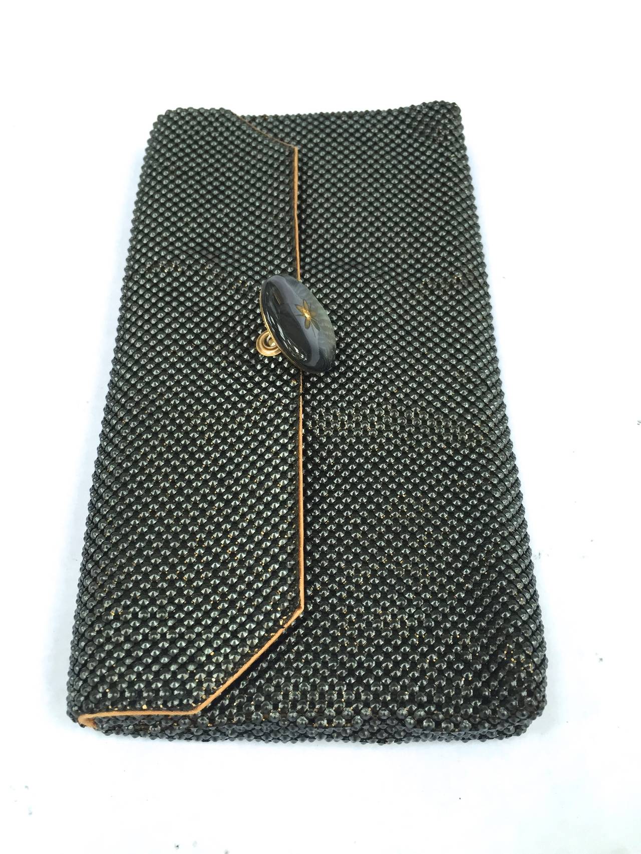 Whiting & Davis 60s black / bronze mesh flip clutch.
Bronze trim. 
Flip round button flower clasp with rhinestone .
Small square mirror wrapped in original envelope.
This clutch appears black but when light hits you see the bronze color making