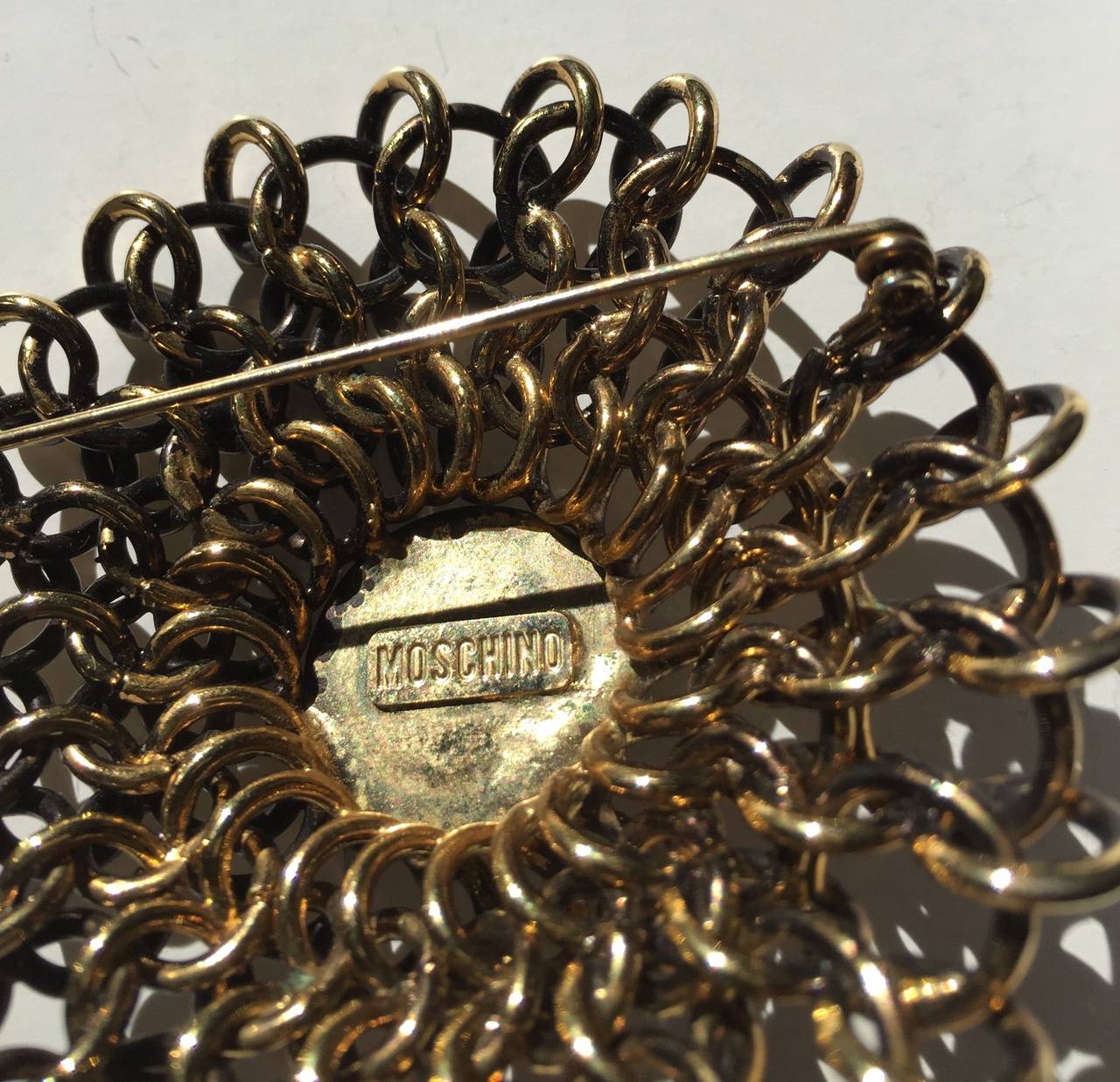 Moschino round gold metal brooch / pin. In Excellent Condition For Sale In Atlanta, GA