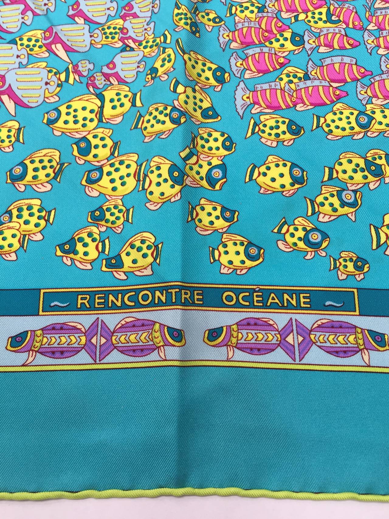 Hermes silk scarf from 2001 'Rencontre Oceane' by Annie Faivre. This is a most elegant colorway with a background in turquoise the color of the Caribbean waters with fish and corals in every bright cheerful color. Annie Faivre has drawn this vibrant
