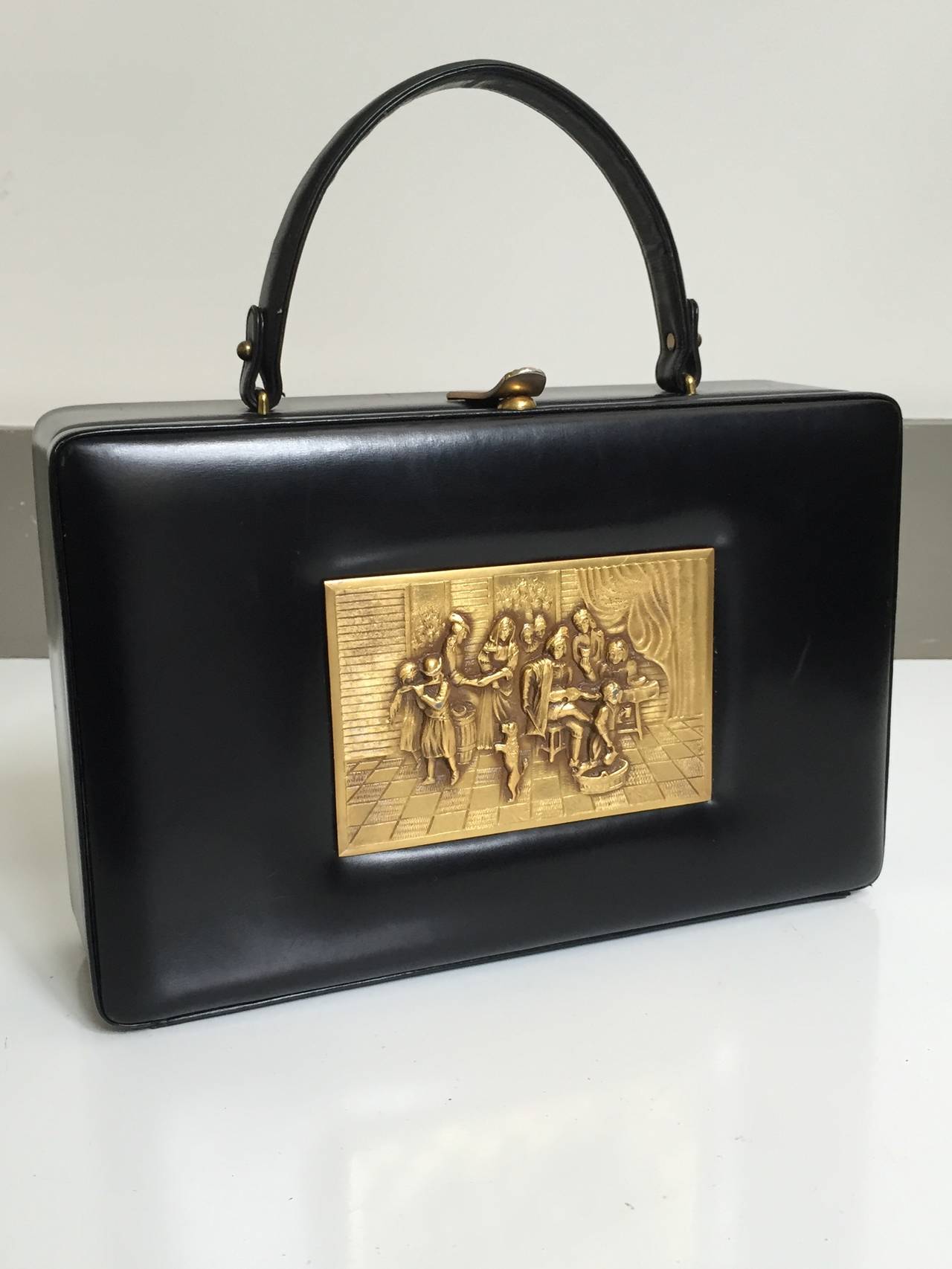 Prestige 1960s French brass relief scene square black leather lunch box style handbag. Interior tan leather is impeccable with two compartments with gold trim. The handle drop is 4