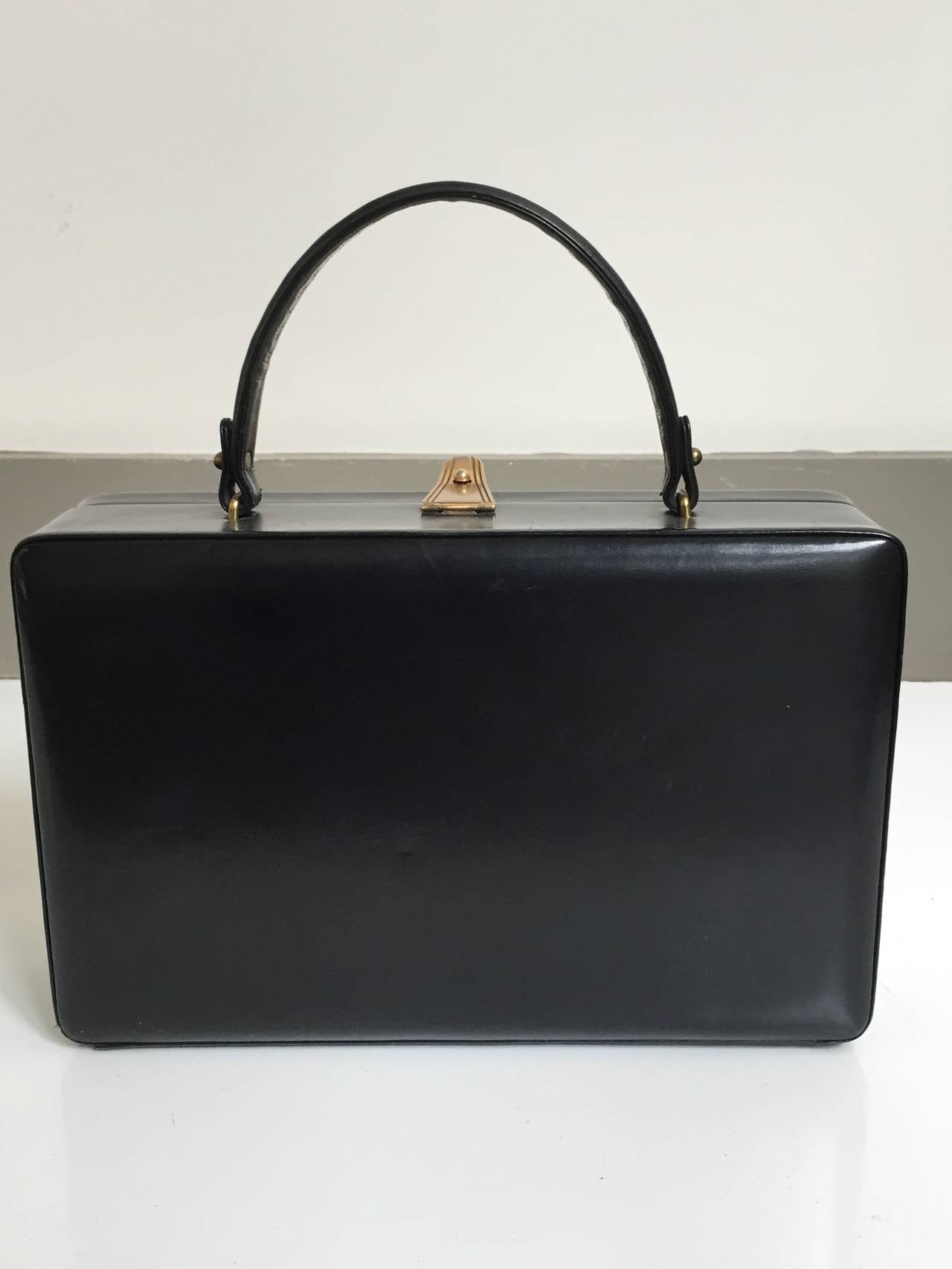 Women's Prestige 60s brass relief black leather handbag.