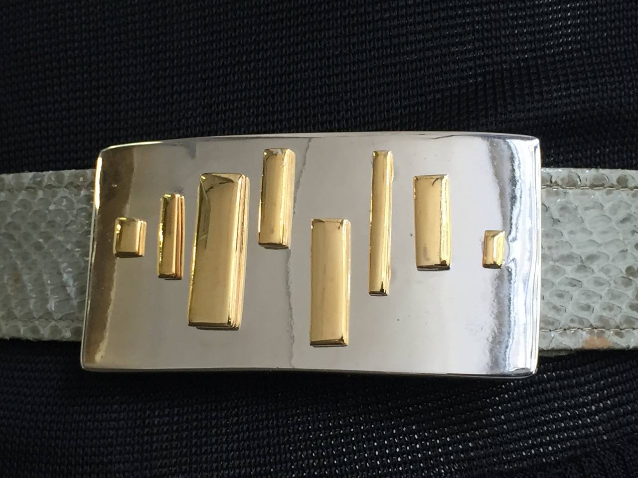 Alexis Kirk 1980s chrome & brass abstract design buckle on green adjustable snake skin belt strap. There are 2 sliders on belt that helps to adjust size which makes this not only stylish but practical. The modern abstract buckle design will only